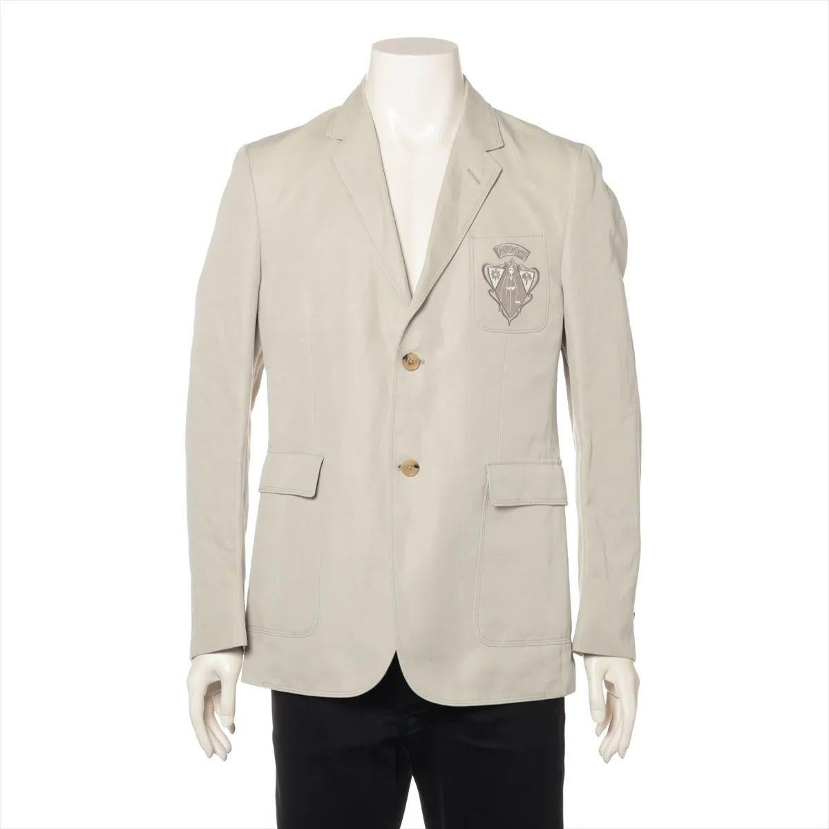 The Gucci Cotton Tailored Suit Jacket in beige showcases the brand’s refined approach to classic menswear. Expertly crafted from high-quality cotton, the jacket features a structured yet comfortable fit with sharp lapels, a single-breasted front,