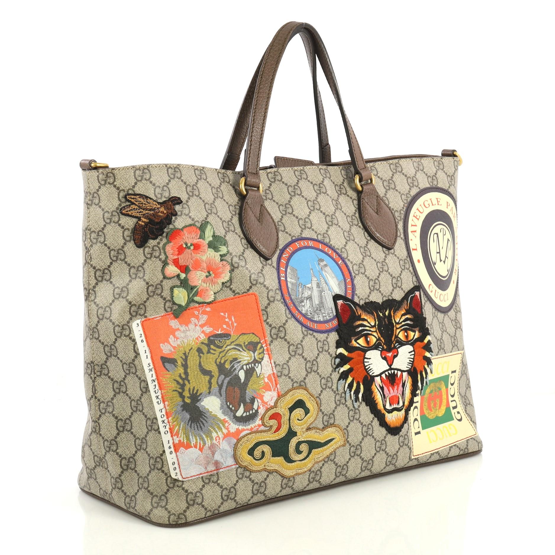 This Gucci Courrier Convertible Soft Open Tote GG Coated Canvas with Applique Large, crafted in brown GG coated canvas, features dual flat leather handles, embroidered applique, and aged gold-tone hardware. Its magnetic closure opens to a neutral