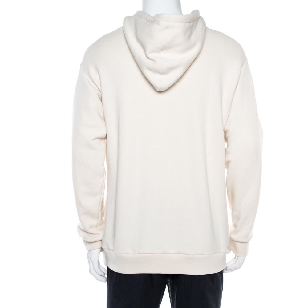 This sweatshirt from Gucci is a closet staple. Crafted from 100% cotton, it comes in a cream hue. This creation features the signature Web stripe details atop which the Gucci logo and 'Dapper Dan' is printed. It comes with a hood and long sleeves.