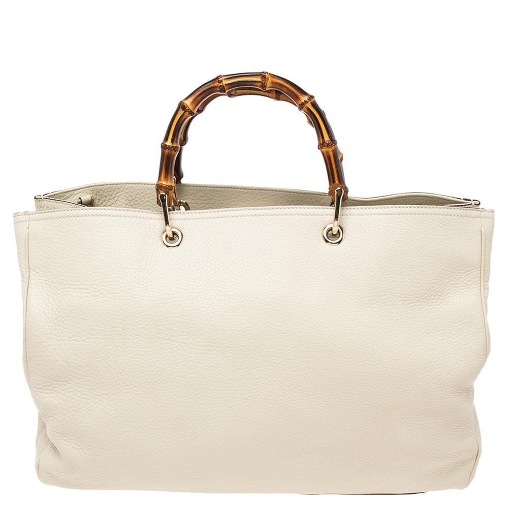 Designed with Gucci’s signature Bamboo top handles, this Shopper tote is instantly recognizable. This elegant style is finely created from cream leather and is finished with an embossed Gucci trademark on the front. The detachable flat leather