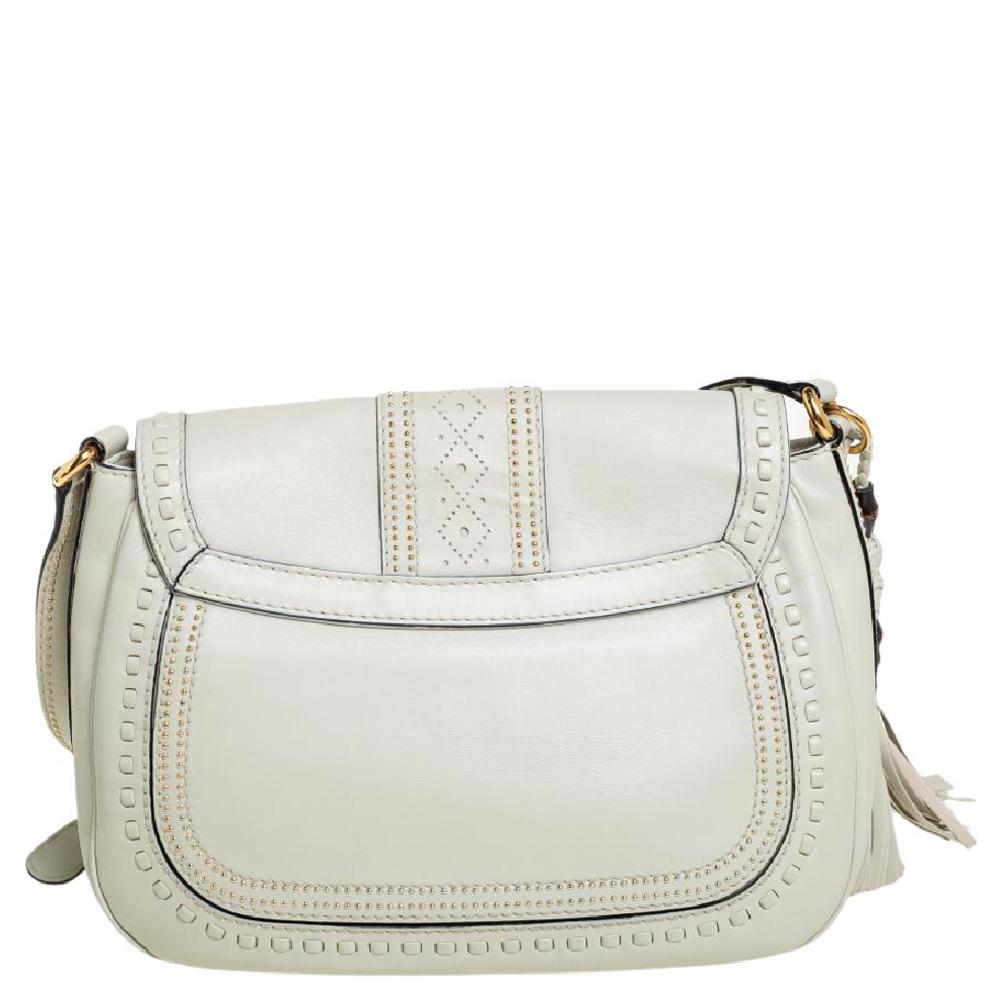 A gorgeous piece for style-conscious women, this small shoulder bag from Gucci is made with cream leather. It is beautifully adorned with stud embellishments and two leather tassels detailed with bamboo and leather monkey fist. The flap features