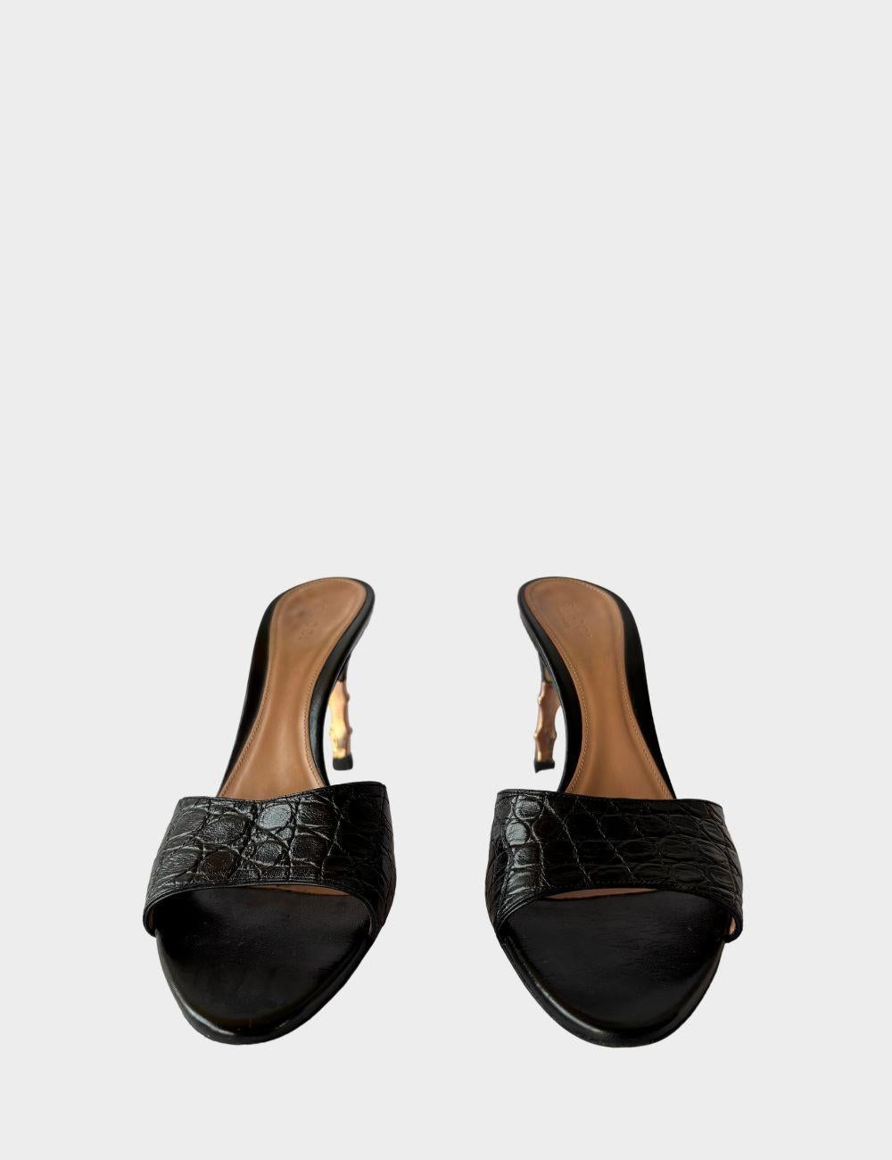 Scopri il glamour sofisticato con queste mules in pelle nera di Gucci, progettate con un tocco moderno e un fascino senza tempo. Caratterizzati da un cinturino in pelle effetto coccodrillo, questi tacchi aperti sono impreziositi da un tacco a spillo