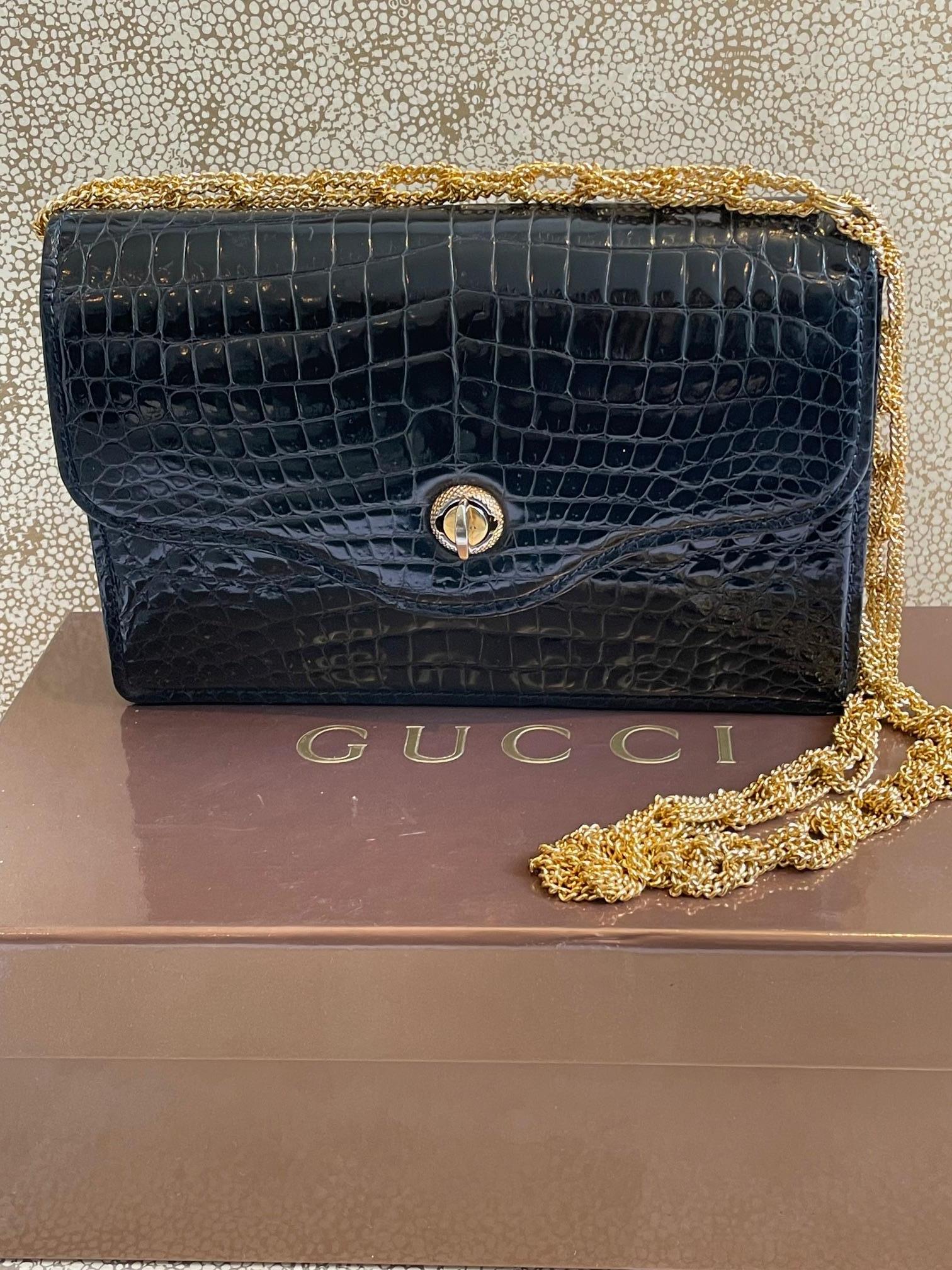 Gucci Crocodile Chain And Turn Lock Clutch  1960s. 

A stunning, very rare vintage Gucci crocodile Porosus clutch bag. It is a very dark navy blue bag (almost black) with navy stitching. It is a flap bag with a gold tone turn lock. The interior is