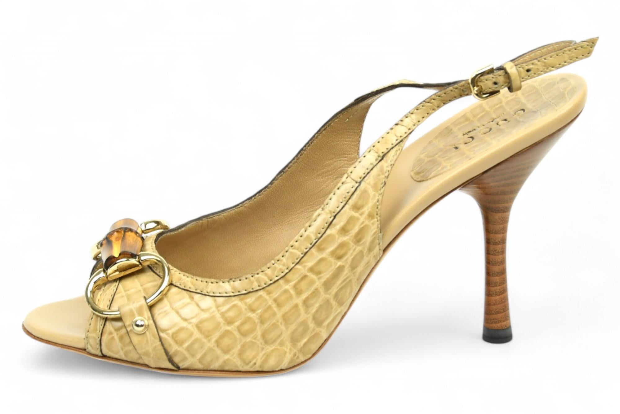 Diese Slingback-Absätze aus beigefarbenem, krokodilgeprägtem Leder sind eine raffinierte Interpretation des charakteristischen Gucci-Pferdemotivs und werden durch das ikonische goldfarbene Pferdegebiss des Hauses veredelt. Die zehenoffene Silhouette
