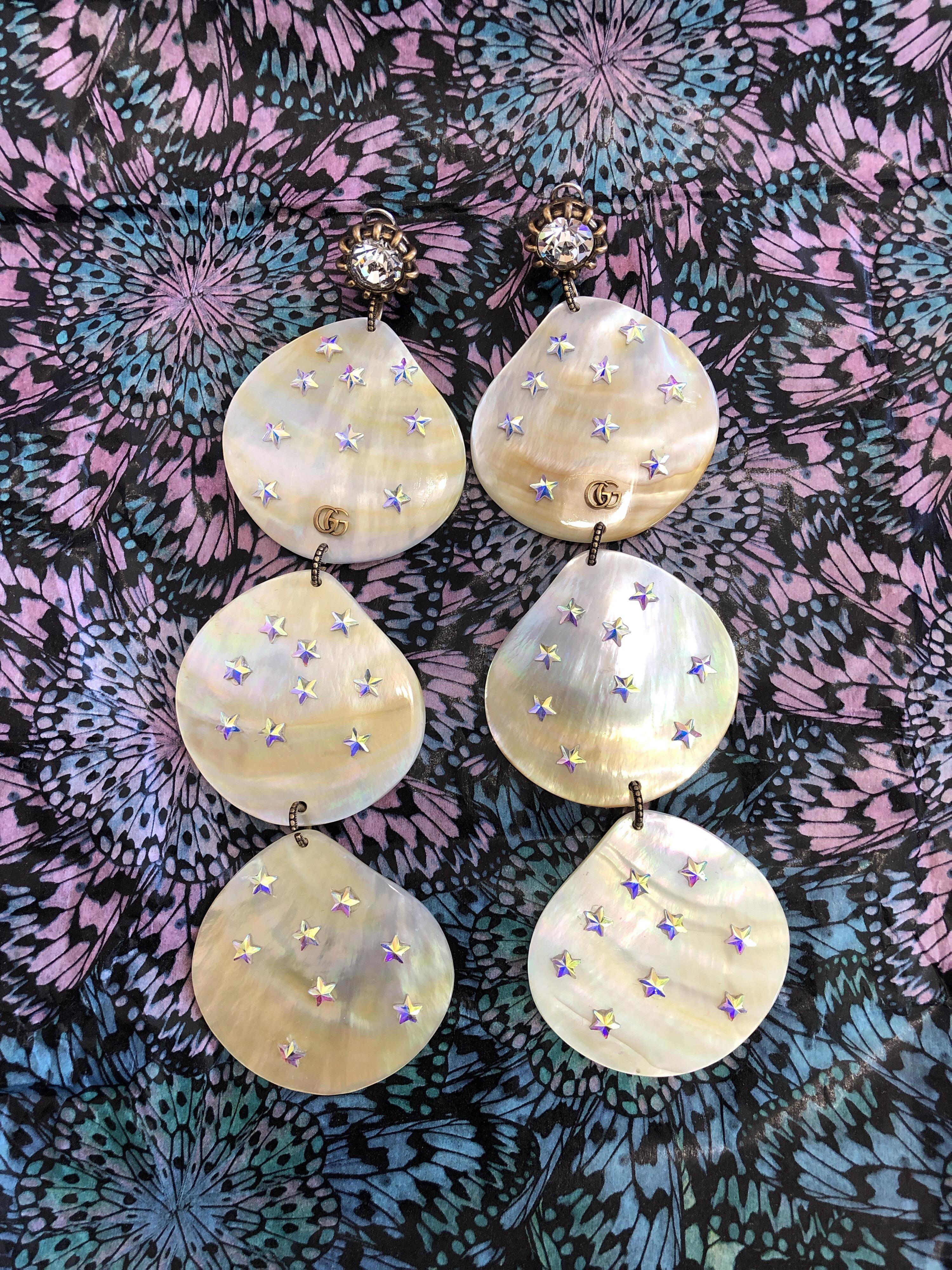 Presented on the Cruise 2019 runway, these statement pendant earrings are made from natural mother of pearl shell, achieving a one-of-a-kind finish for each unique piece. Dangling from faceted crystals, three tiered shells are each dotted with