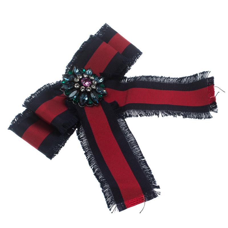 Add a subtle hint of drama to your outfits for the parties or even those casual chic events using this beautiful Gucci bow brooch. Designed from blue and red web patterned grosgrain ribbon, it is frayed around the edges and further enhanced with a