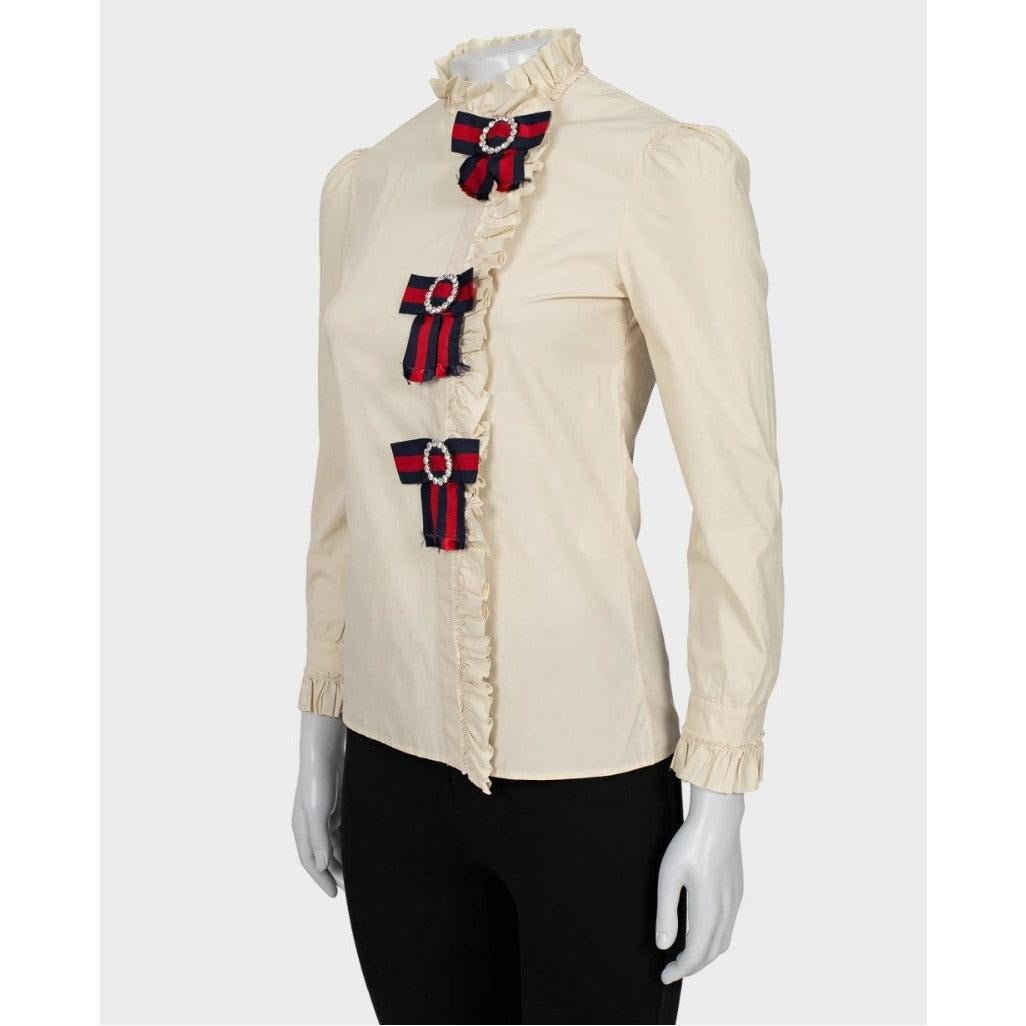 Aggiungi un tocco di glamour iconico di Gucci al tuo guardaroba con questa camicia elegante! Realizzata in un comodo misto cotone elasticizzato, questa abbottonatura beige presenta scintillanti decorazioni a fiocco in cristallo che catturano