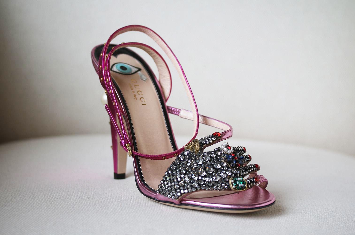 Gucci's metallic fuschia and light-pink leather sandals are pierced with 'GG'-embellished Swarovski pearls and gold studs at the cone heel.
This runway pair is strewn with glistening jewels along each strap, while the right shoe is adorned with a