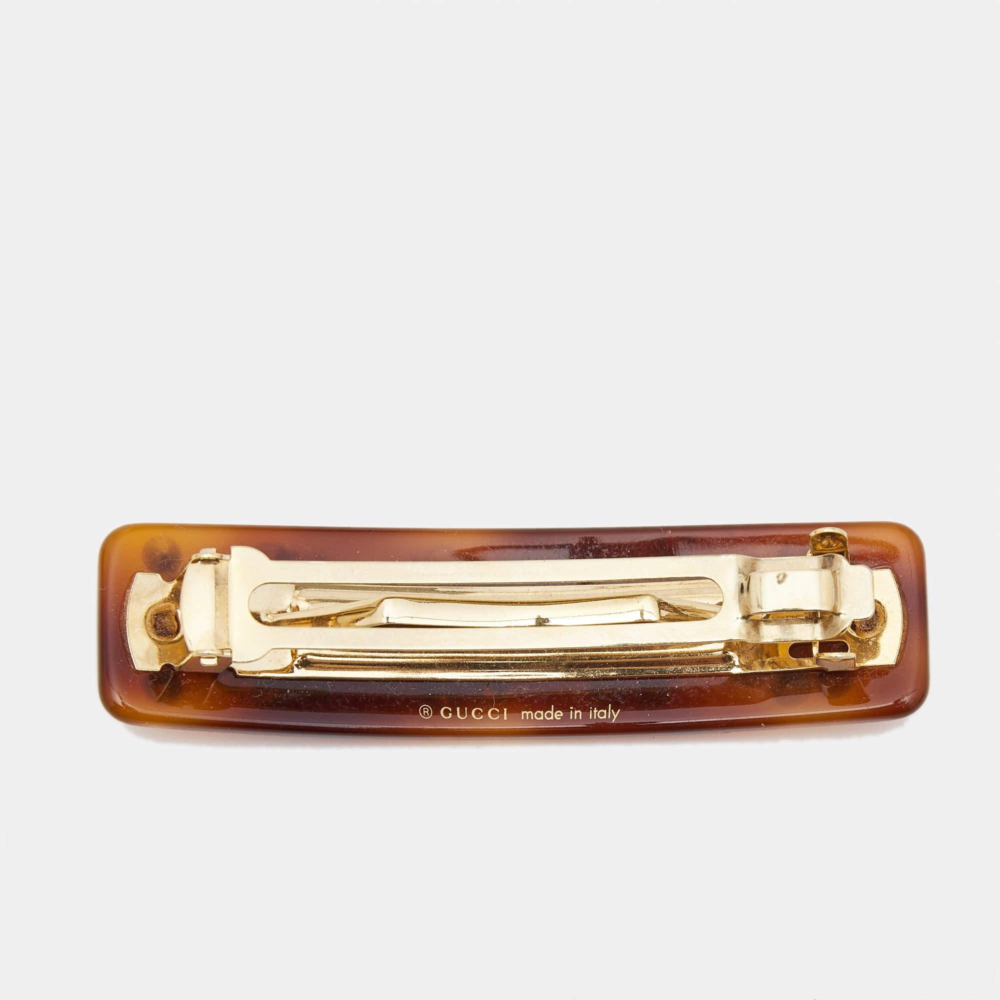 Sparkling crystals and the brand logo are set on resin to form this sweet Gucci hair clip. It has a simple gold-tone clasp at the back.

