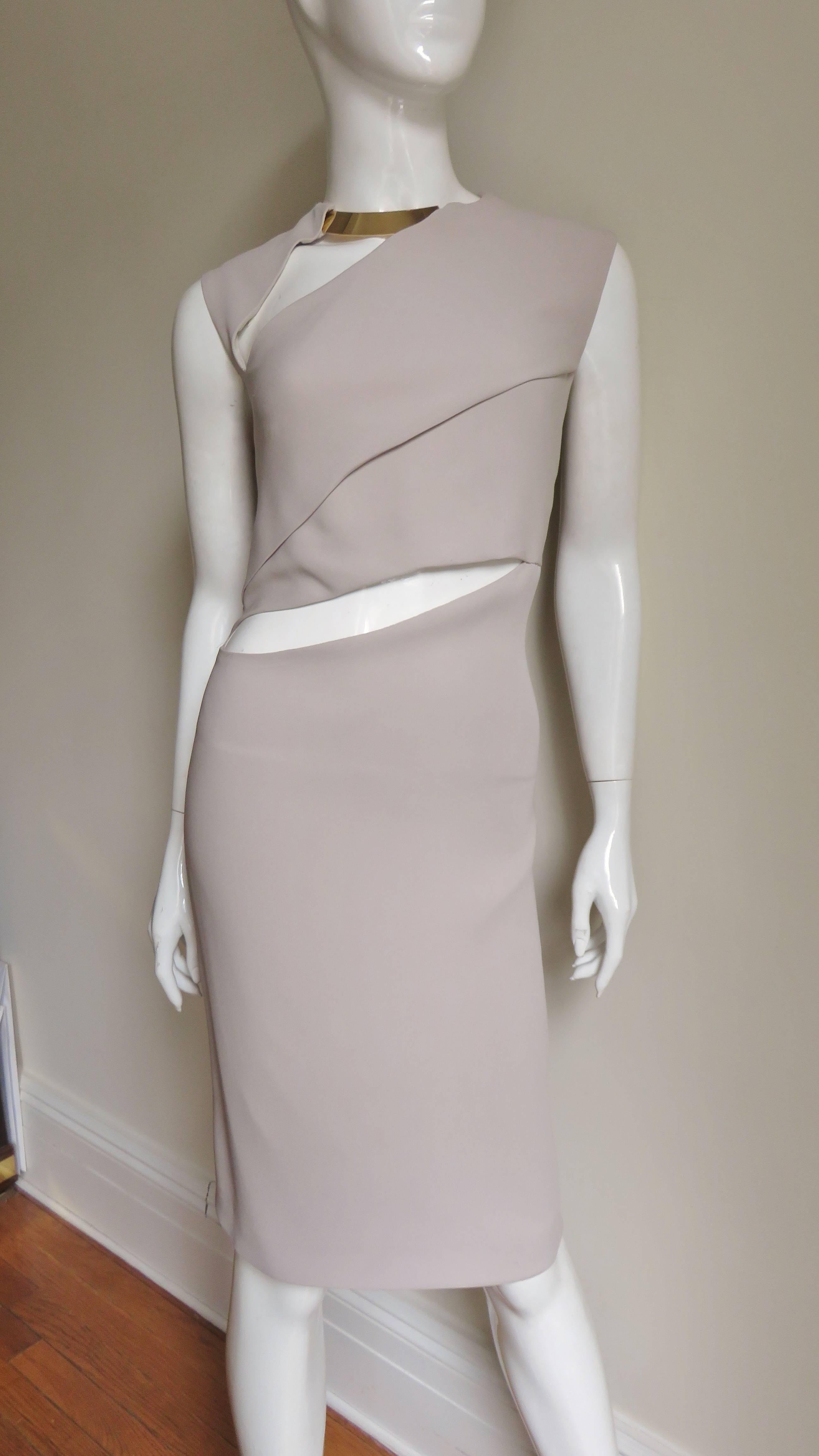 A fabulous light taupe dress by Tom Ford for Gucci.  It has a gold metal collar exposed at the front neck with a diagonal wedge cut out below it, another cut out and fold diagonally are at the waist.  The skirt is straight, there is a matching back