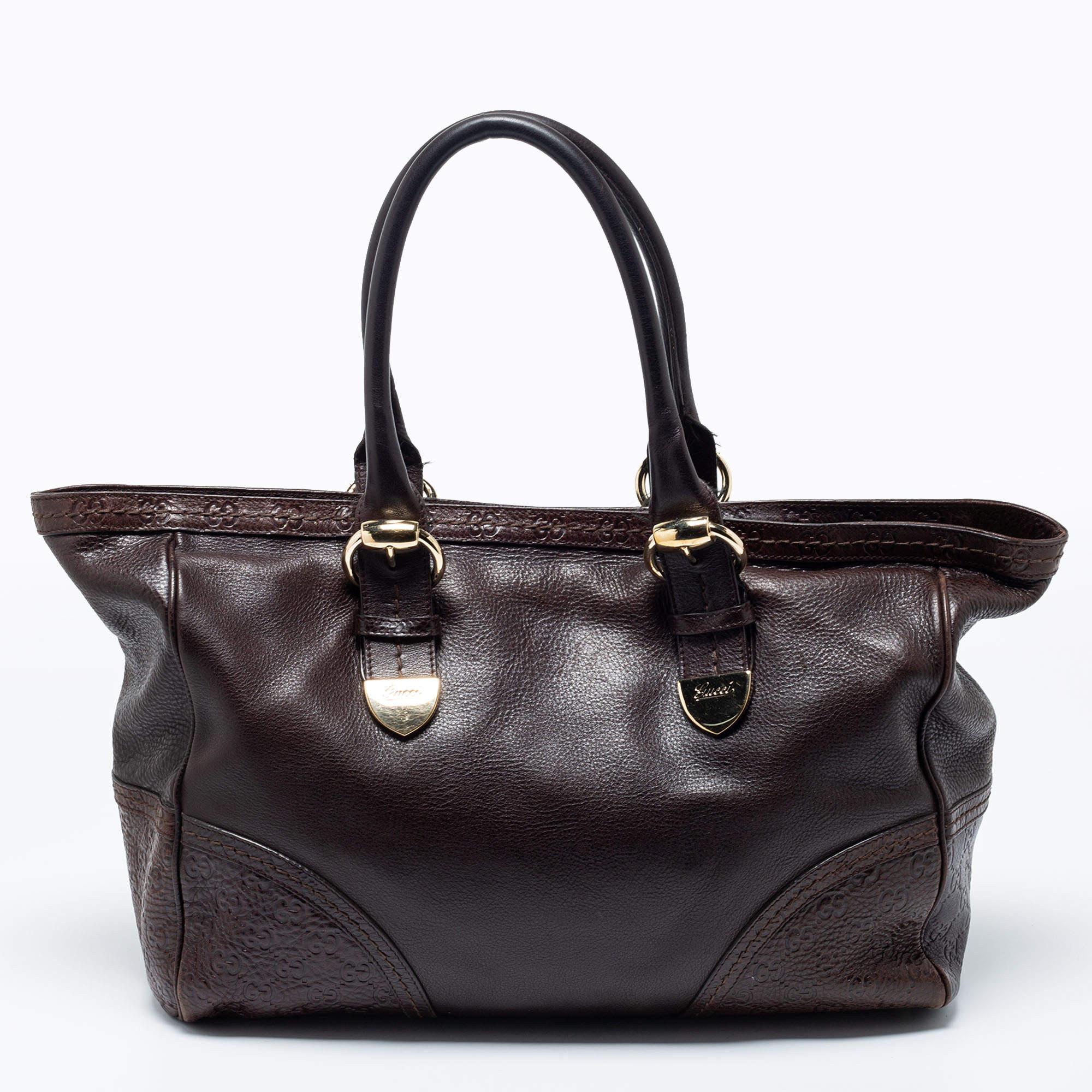 Skillfully crafted from signature leather, this women's tote is from the house of Gucci. The dark brown bag has a spacious size, dual handles, and gold-tone details. It is an excellent companion for everyday use.

Includes: Original Dustbag

