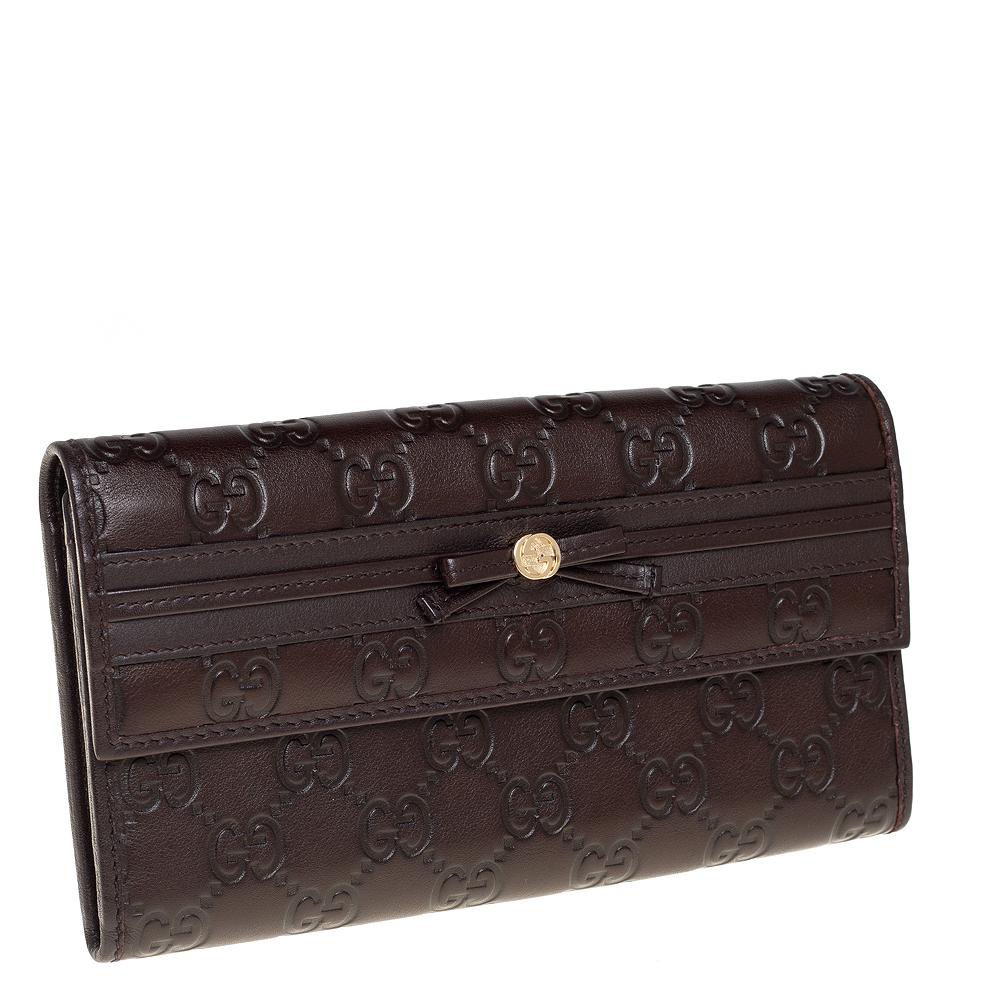 Made of signature Guccissima leather in dark brown, this continental wallet from Gucci is a classy choice. The snap button opens to multiple card slots, open compartments, and a zipped pocket. This wallet is complete with bow detail on the flap.

