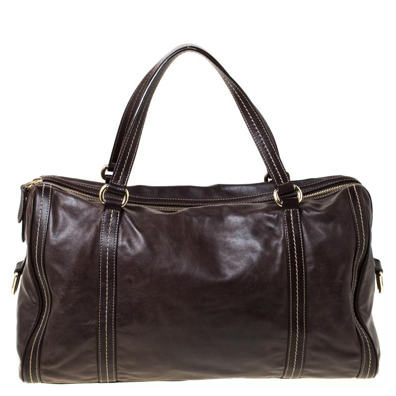 A truly posh and elegant piece to add to your collection. This Boston Bag by Gucci is crafted from brown leather and styled with a metal bow detail on the front. It features a top zip closure, two handles, protective metal feet, and a spacious