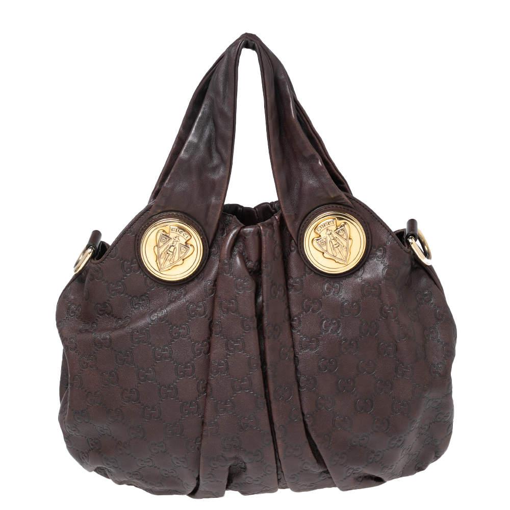 Let your everyday style look cute and chic with this Hysteria hobo from the House of Gucci. It is designed using dark-brown leather, with gold-tone logos embellishing its silhouette. It comes with two top handles, a spacious interior, and gold-tone
