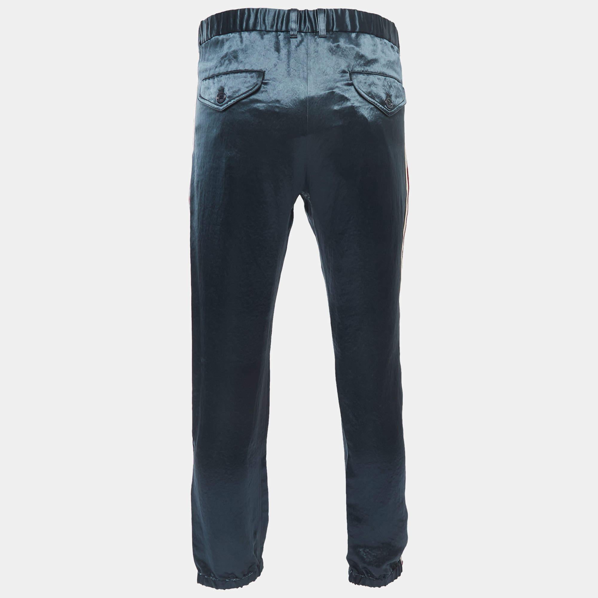The Gucci trousers exude luxury with their deep green satin fabric. They feature the iconic Gucci web stripe along the sides, adding a touch of elegance. These relaxed-fit trousers offer both comfort and high-end style for fashion-forward