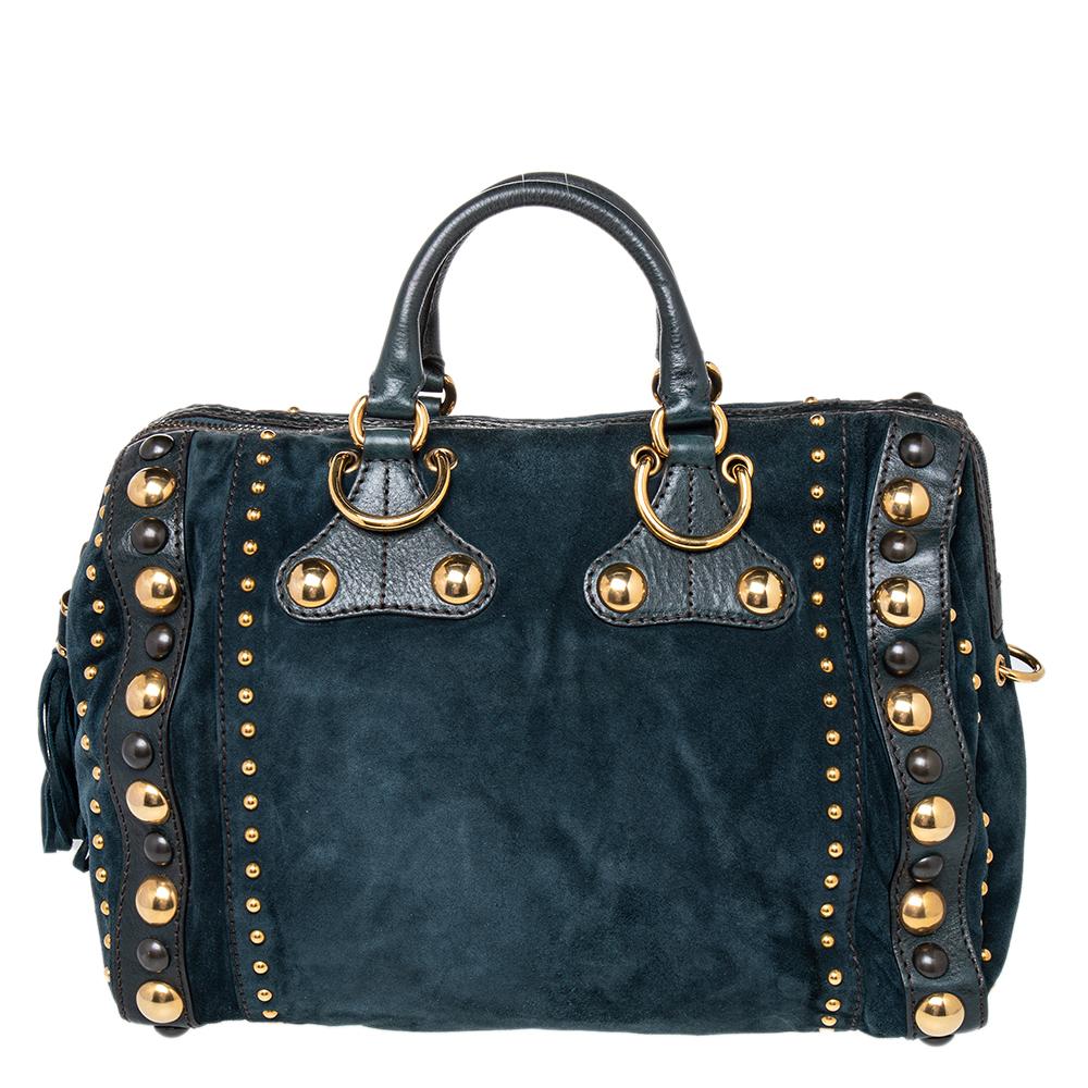 Crafted from dark green suede and leather, this Gucci number has tassels and a spacious fabric interior. It also features two handles, a signature heart emblem, and studs in gold-tone hardware. Flaunt this beauty wherever you go and you'll surely