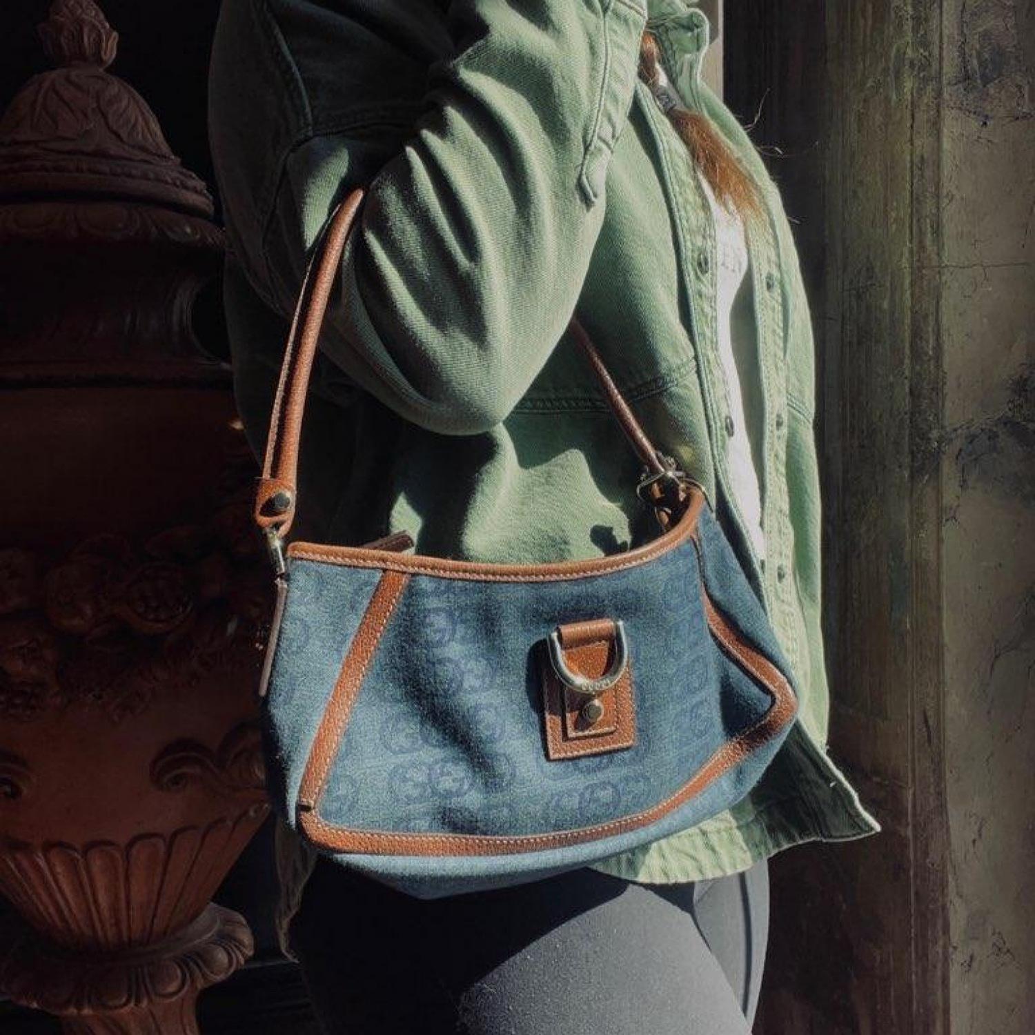 This Gucci D Ring Abbey Pochette Bag was made in Italy and it is finely crafted a blue denim and leather exterior with gold-tone hardware features. It has a rolled leather top handle. It has a zipper closure that opens up to a spacious brown twill