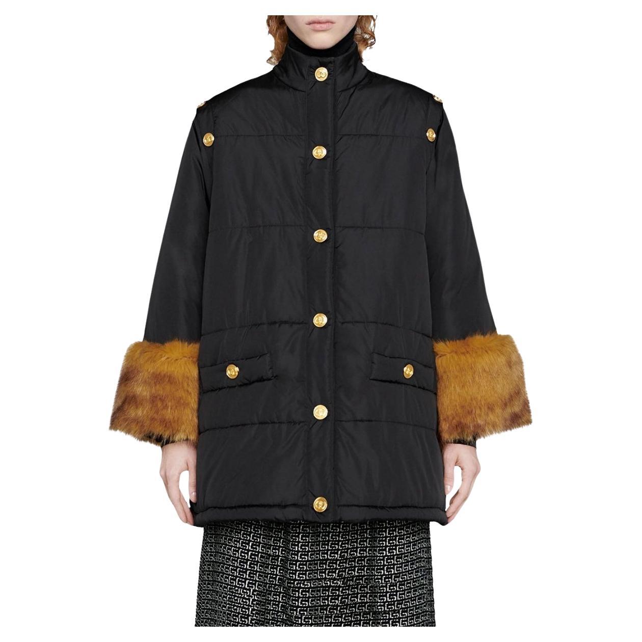 Black padded jacket from Gucci with detachable sleeves. The oversized fit keeps the silhouette looking modern and relaxed. 
Faux fur cuffs
Embossed gold-tone buttons. 
Stand up collar
Front button fastening
Faux fur trim
Two front