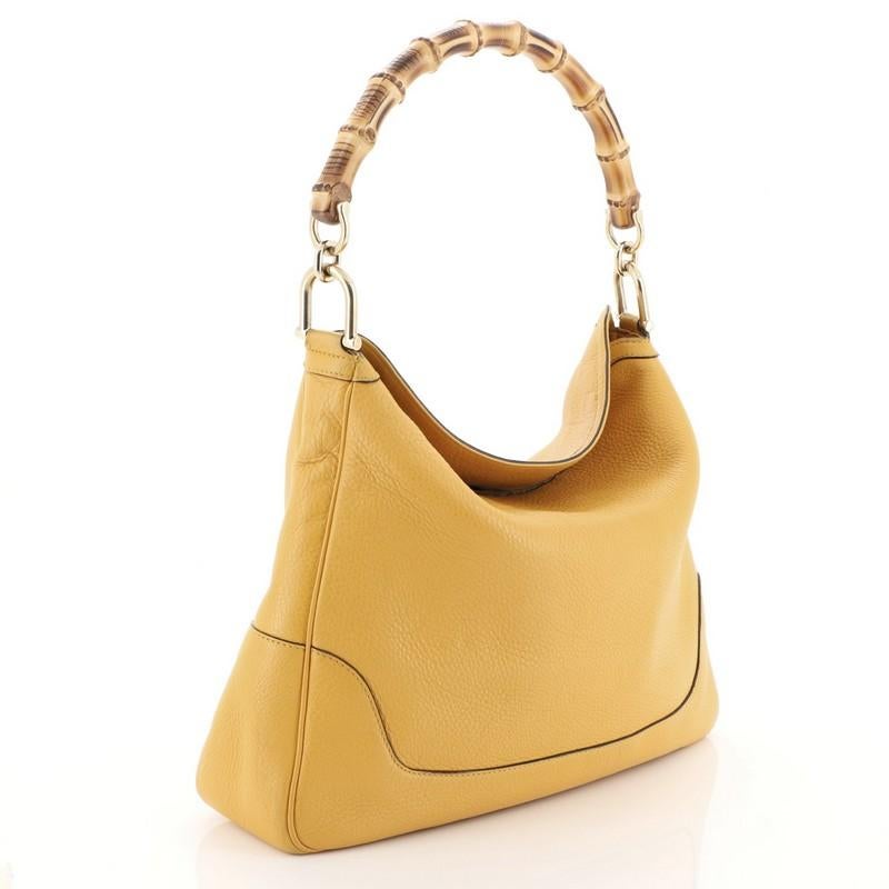 This Gucci Diana Bamboo Shoulder Bag Leather Medium, crafted from yellow leather, features a single looped bamboo handle and gold-tone hardware. It opens to a neutral fabric interior with side zip and slip pockets. 

Estimated Retail Price: