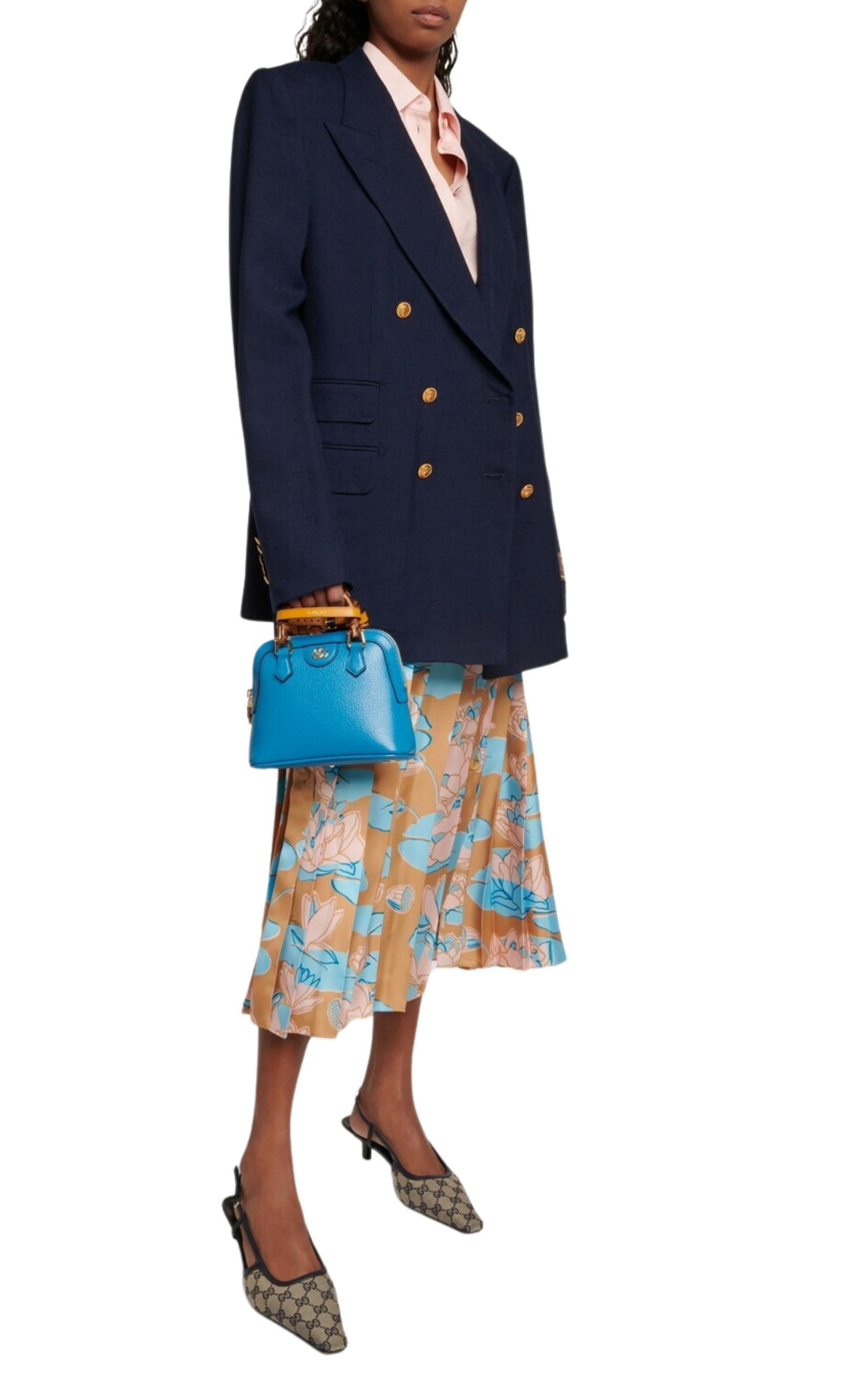 The blue leather Gucci Diana Mini Tote features shiny gold detailing. It comes equipped with two decorative straps to help maintain the shape of the handles, as shown in the photo. The microfiber lining has a luxurious faux suede finish, and there