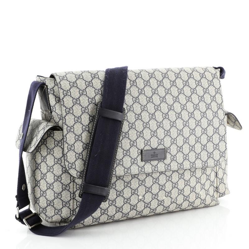 This Gucci Diaper Bag GG Coated Canvas, crafted from blue GG coated canvas, features exterior side pockets with velcro closure, adjustable nylon shoulder strap with leather pad and snap buttons to attach to stroller handles, and silver-tone