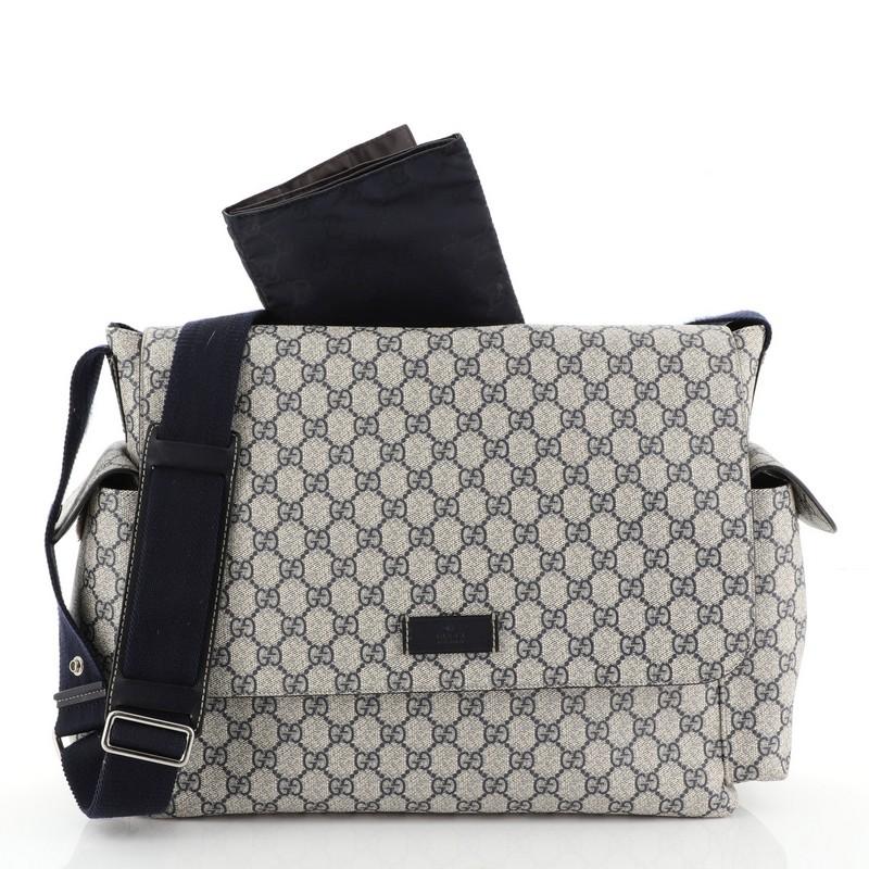This Gucci Diaper Bag GG Coated Canvas, crafted from blue GG coated canvas, features exterior side pockets with velcro closure, adjustable nylon shoulder strap with leather pad and snap buttons to attach to stroller handles, and silver-tone