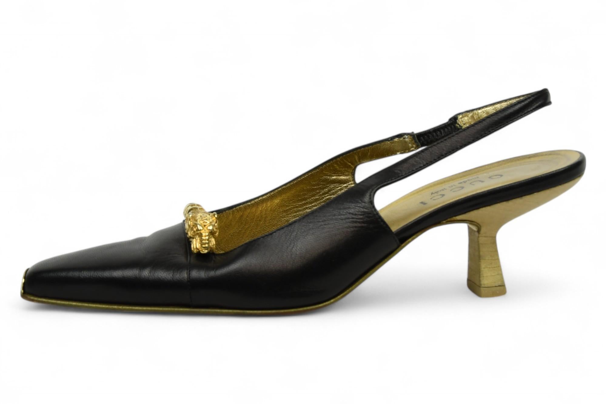 Aggiungi un tocco regale alla tua collezione con queste slingback vintage di Gucci, realizzate in morbida pelle nera e impreziosite da tacchi scultorei color oro. Caratterizzate da un ornamento dorato a forma di testa di leone sulla tomaia e da