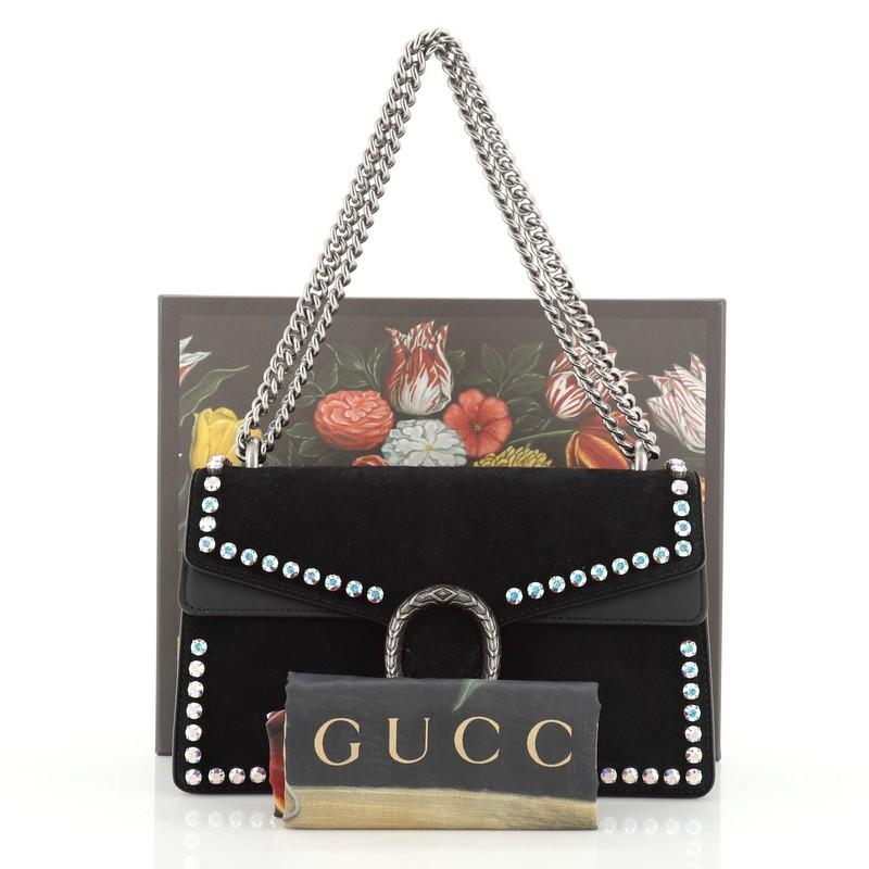 This Gucci Dionysus Bag Crystal Embellished Suede Small, crafted from black suede, features a chain link strap, rhinestone embellishments, textured tiger head spur detail on its flap, and aged silver-tone hardware. Its hidden push-pin closure opens