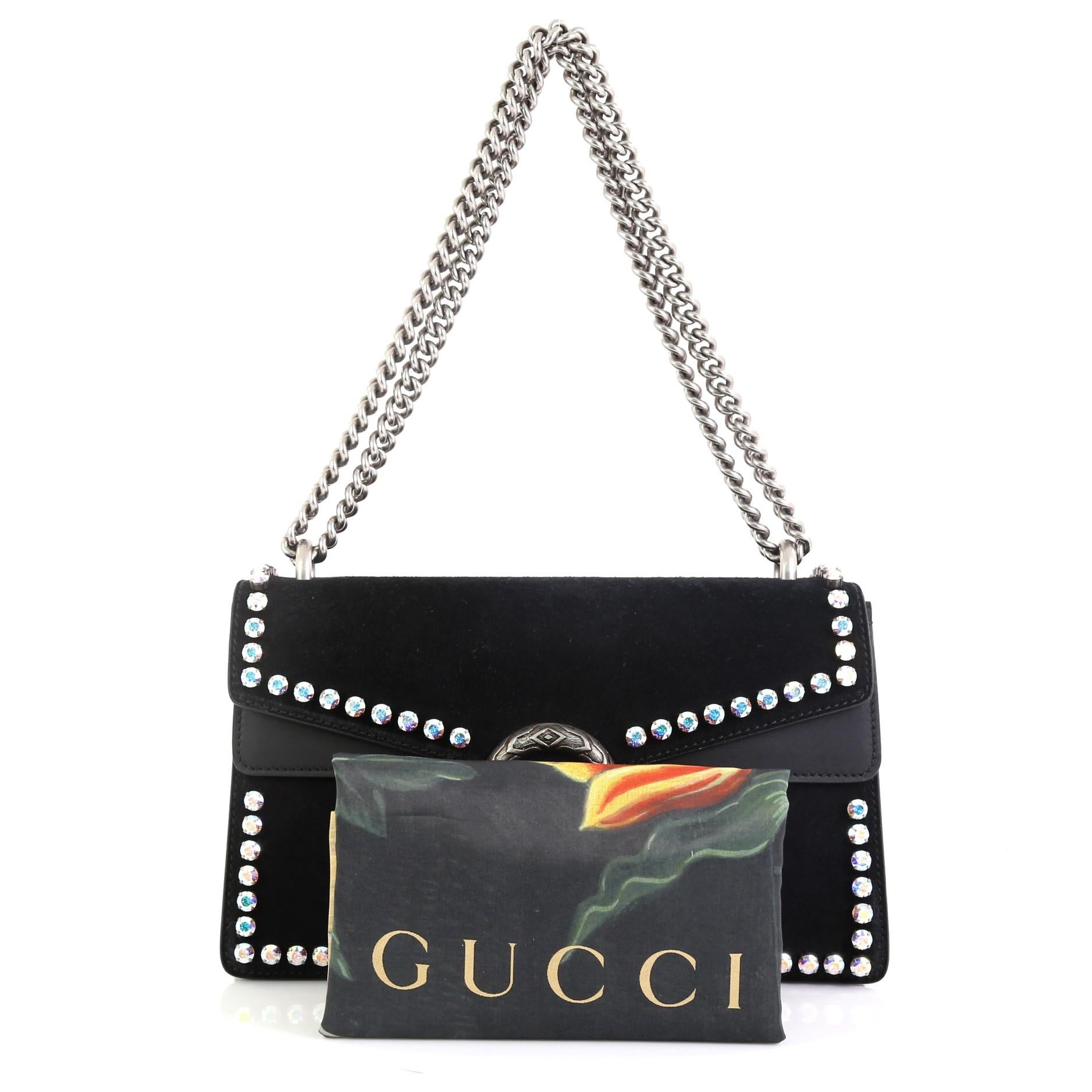 
This Gucci Dionysus Bag Crystal Embellished Suede Small, crafted from black suede, features a chain link strap, rhinestone embellishments, textured tiger head spur detail on its flap, and aged silver-tone hardware. Its hidden push-pin closure opens