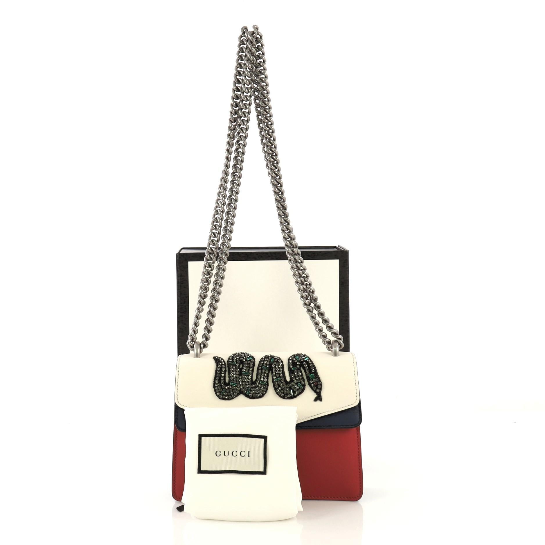 This Gucci Dionysus Bag Embellished Leather Mini, crafted from white, navy, and red embellished leather, features a chain link strap, textured tiger head spur detail on its flap, and silver-tone hardware. Its hidden push-pin closure opens to a beige