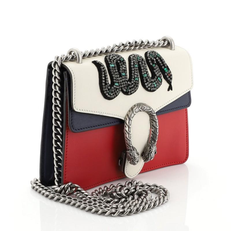 This Gucci Dionysus Bag Embellished Leather Mini, crafted from white, blue, and red embellished leather, features a chain link strap, textured tiger head spur detail on its flap, and aged silver-tone hardware. Its hidden push-pin closure opens to a