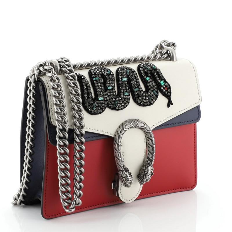 This Gucci Dionysus Bag Embellished Leather Mini, crafted from red and multicolor embellished leather, features chain link strap, textured tiger head spur detail on its flap, and aged silver-tone hardware. Its hidden push-pin closure opens to a