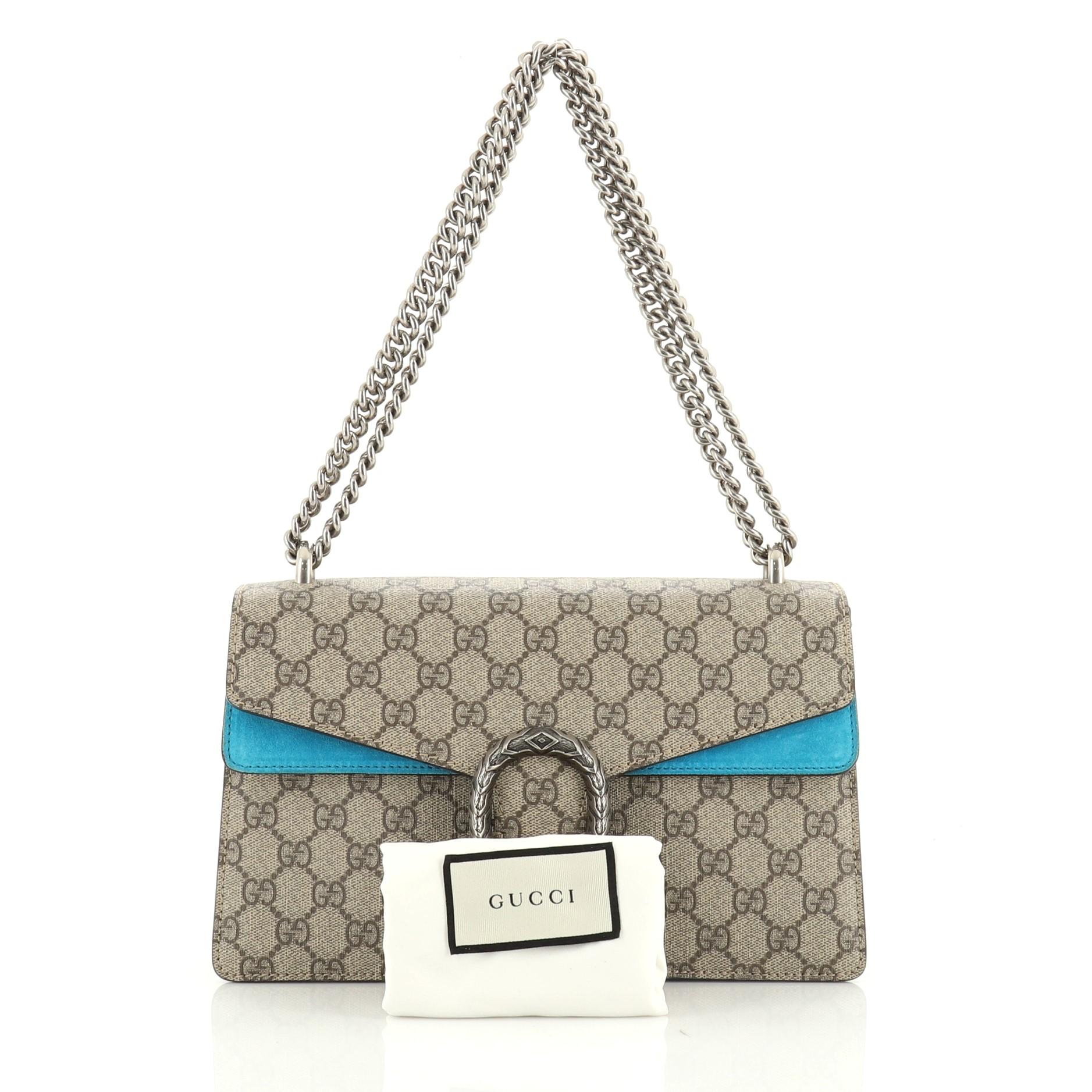 This Gucci Dionysus Bag GG Coated Canvas Small, crafted from brown GG coated canvas, features a sliding chain strap, tiger head spur detail on flap, and aged silver-tone hardware. Its pin closure opens to a blue suede interior with two open