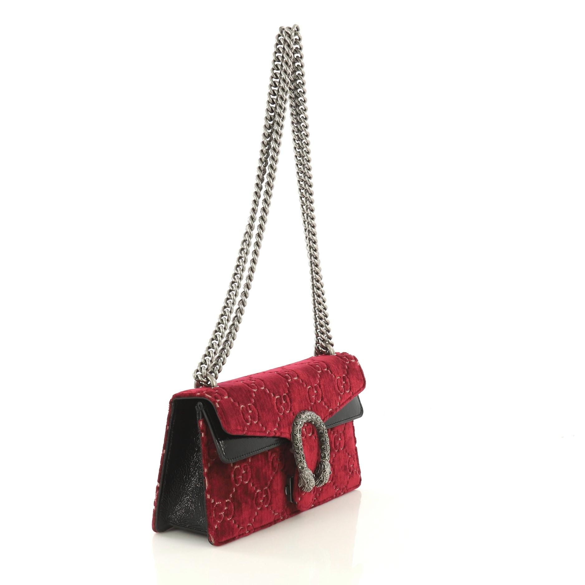 This Gucci Dionysus Bag GG Velvet Mini, crafted from red GG velvet, features chain link strap, textured tiger head spur detail on its flap, and aged silver-tone hardware. Its hidden push-pin closure opens to a neutral microfiber interior.