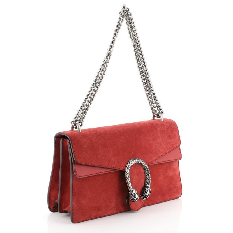 This Gucci Dionysus Bag Suede Small, crafted from red suede, features a chain link strap, embellished tiger head spur detail on its flap, accordion-like gusseted sides, and aged silver-tone hardware. Its hidden push-pin closure opens to a red
