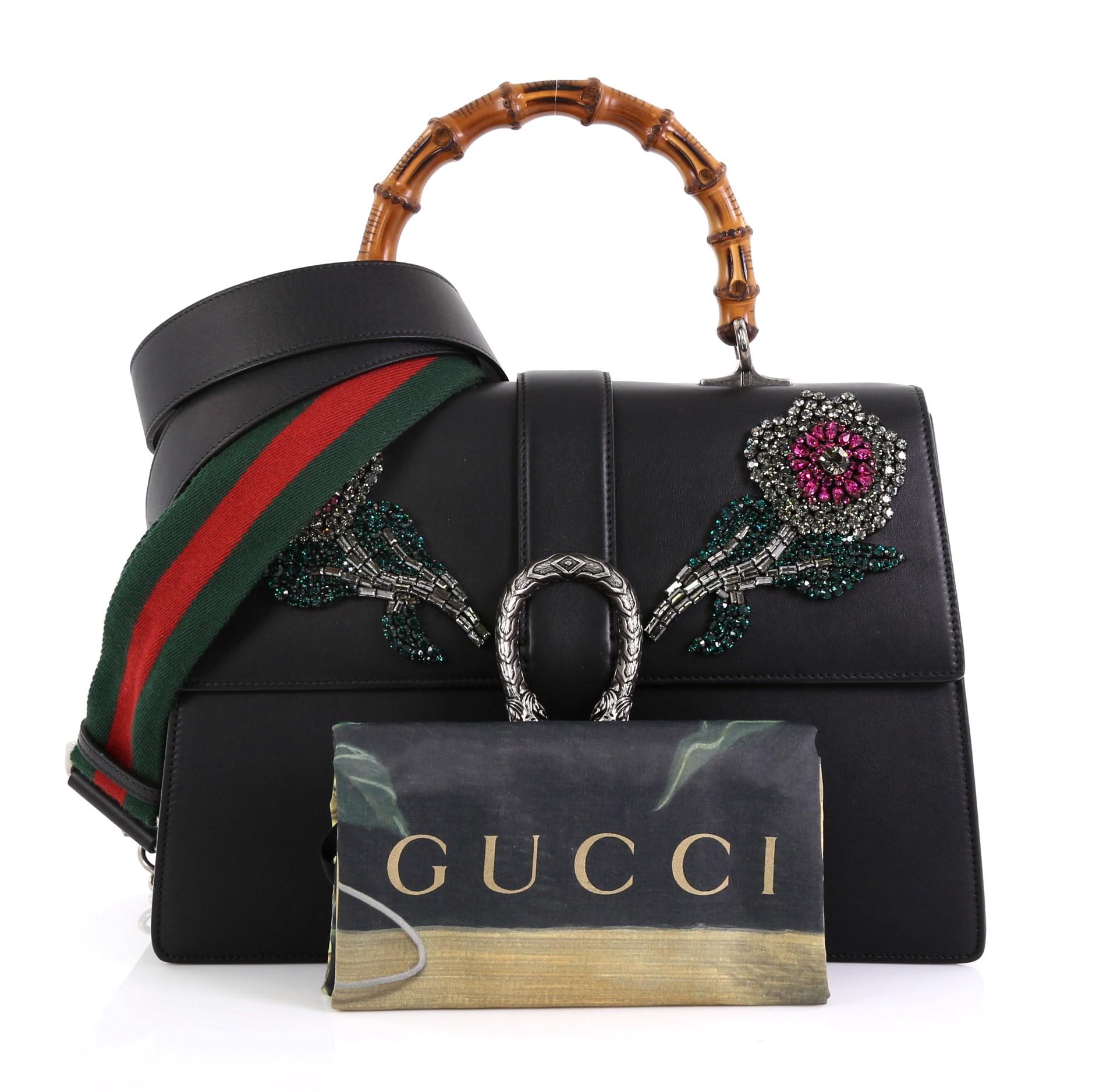 This Gucci Dionysus Bamboo Top Handle Bag Embellished Leather Large, crafted in black embellished leather, features bamboo top handle, multicolored beaded floral embellishment, textured tiger head spur detail, and aged silver-tone hardware. Its flap