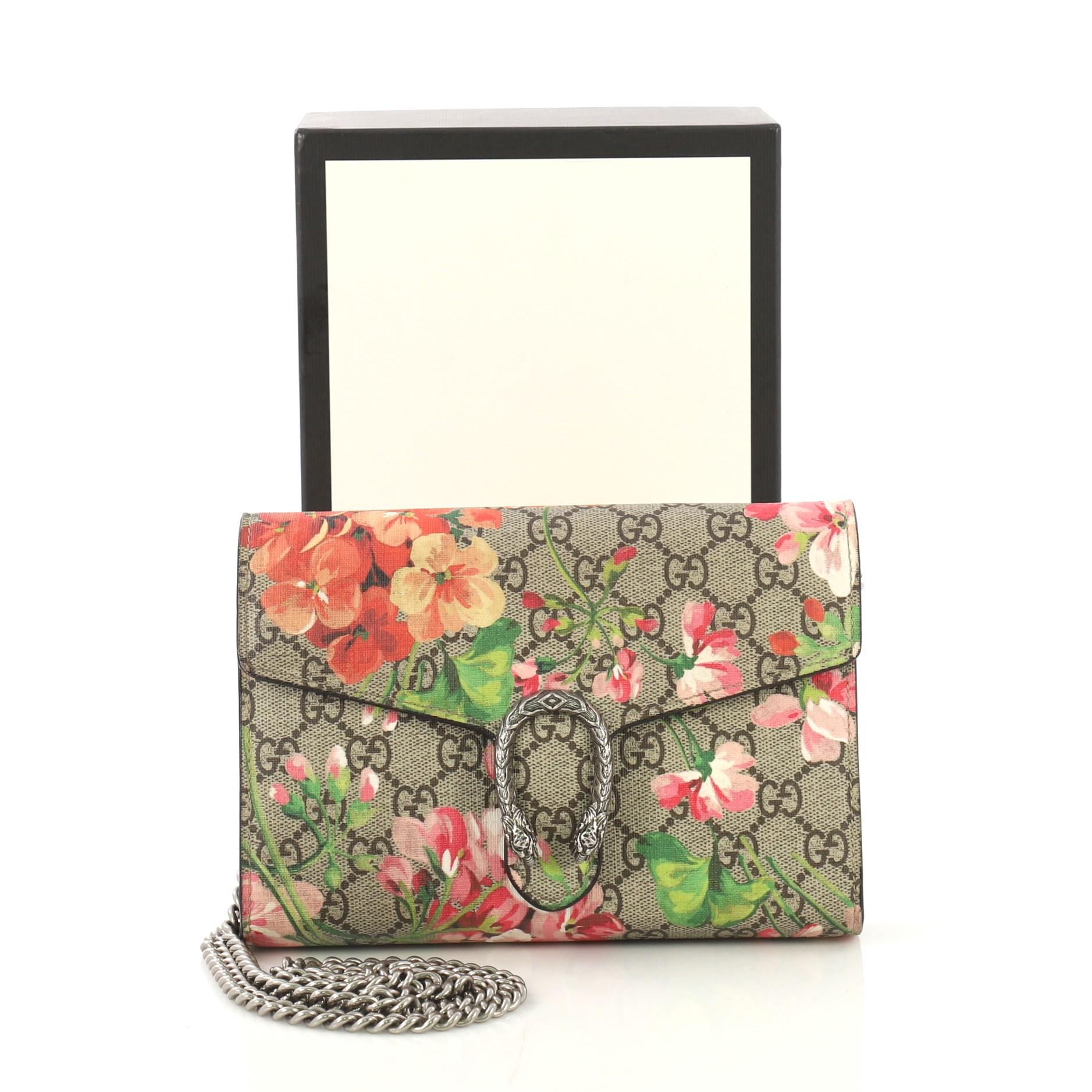 This Gucci Dionysus Chain Wallet Blooms Print GG Coated Canvas Small, crafted from brown blooms print GG coated canvas, features chain link strap, textured tiger head spur detail on its flap, and aged silver-tone hardware. Its snap button closure