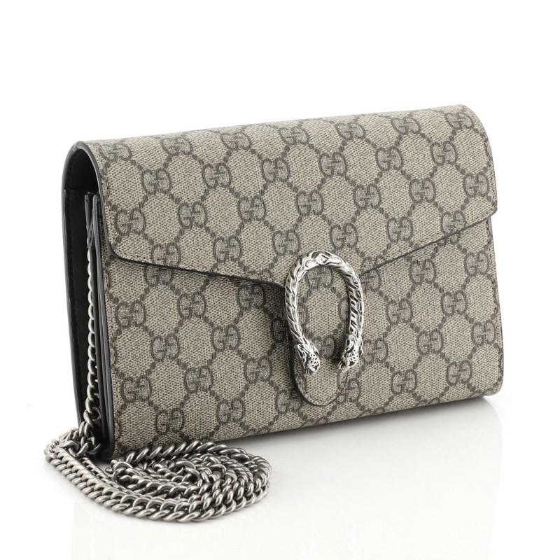 This Gucci Dionysus Chain Wallet GG Coated Canvas Small, crafted from brown GG coated canvas, features a chain link strap, textured tiger head spur detail on its flap, and aged silver-tone hardware. Its hidden push-pin closure opens to a black nylon