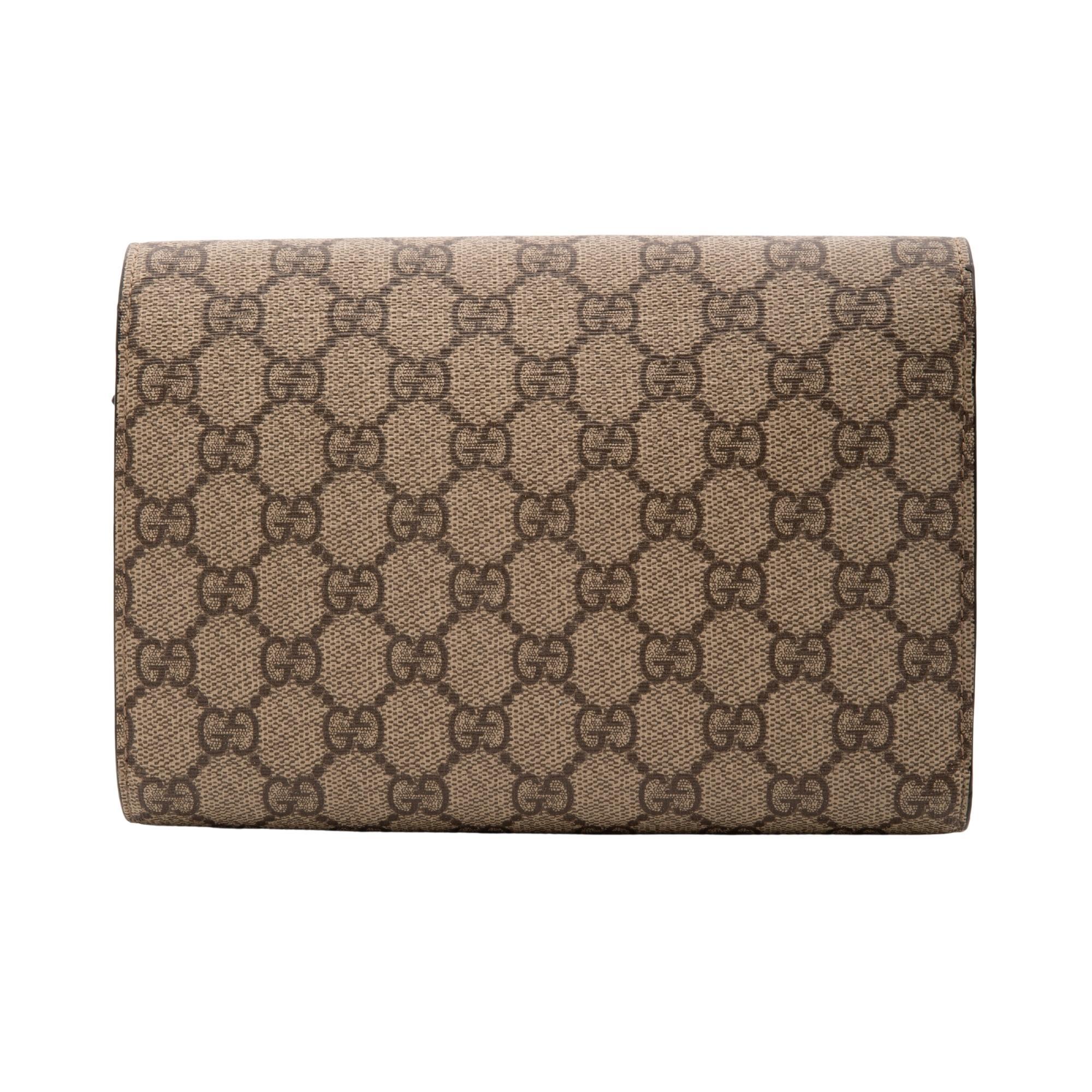 This structured crossbody wallet on chain bag from Gucci is made with GG Supreme canvas and features a textured tiger head spur on the front flap, antiqued silver-toned hardware, 16 card slots and two bill compartments, three separate interior