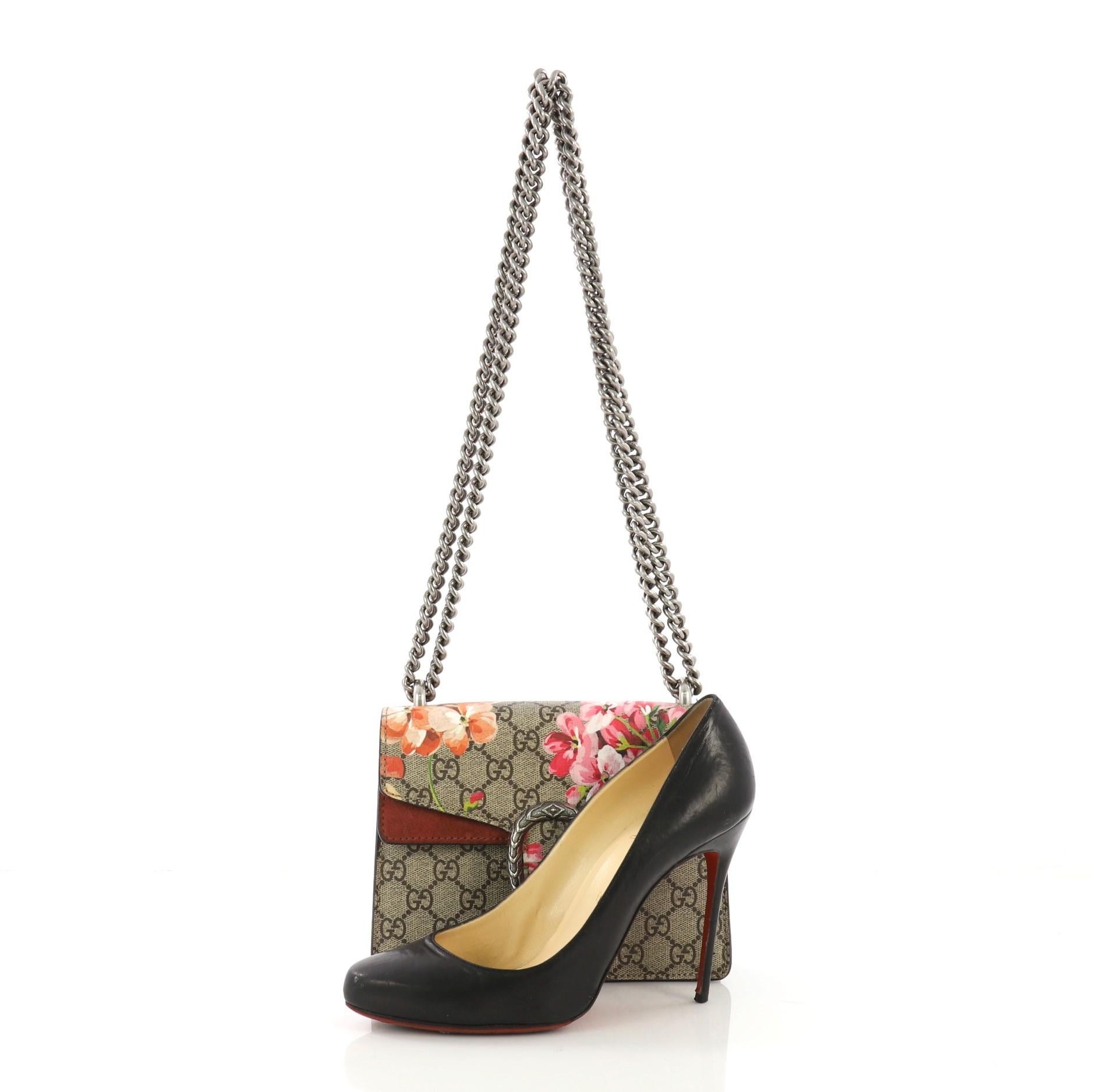 This Gucci Dionysus Handbag Blooms Print GG Coated Canvas Mini, crafted from beige blooms print GG coated canvas, features sliding chain strap, tiger head spur, and aged silver-tone hardware. Its pin closure opens to a purple suede interior. **Note: