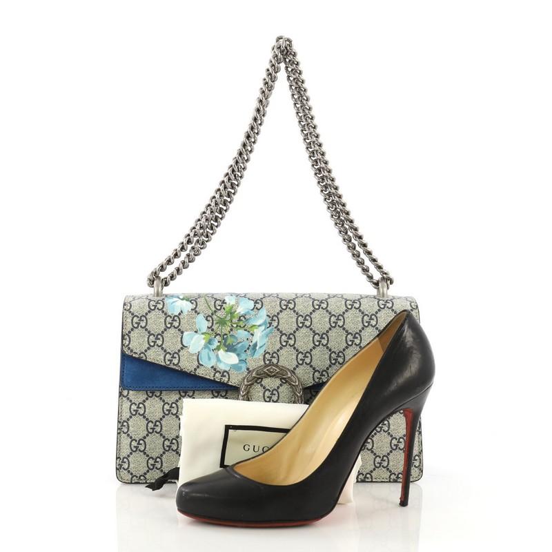 This Gucci Dionysus Handbag Blooms Print GG Coated Canvas Small, crafted from blue blooms print GG coated canvas, features sliding chain strap, tiger head spur detail, and matte silver-tone hardware. Its pin closure opens to a blue suede interior