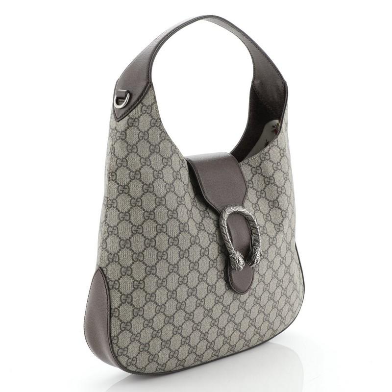 This Gucci Dionysus Hobo GG Coated Canvas Medium, crafted in brown GG coated canvas, features single loop leather handle, textured tiger head spur detail on its flap tab, and aged silver-tone hardware. It opens to a floral print fabric interior with