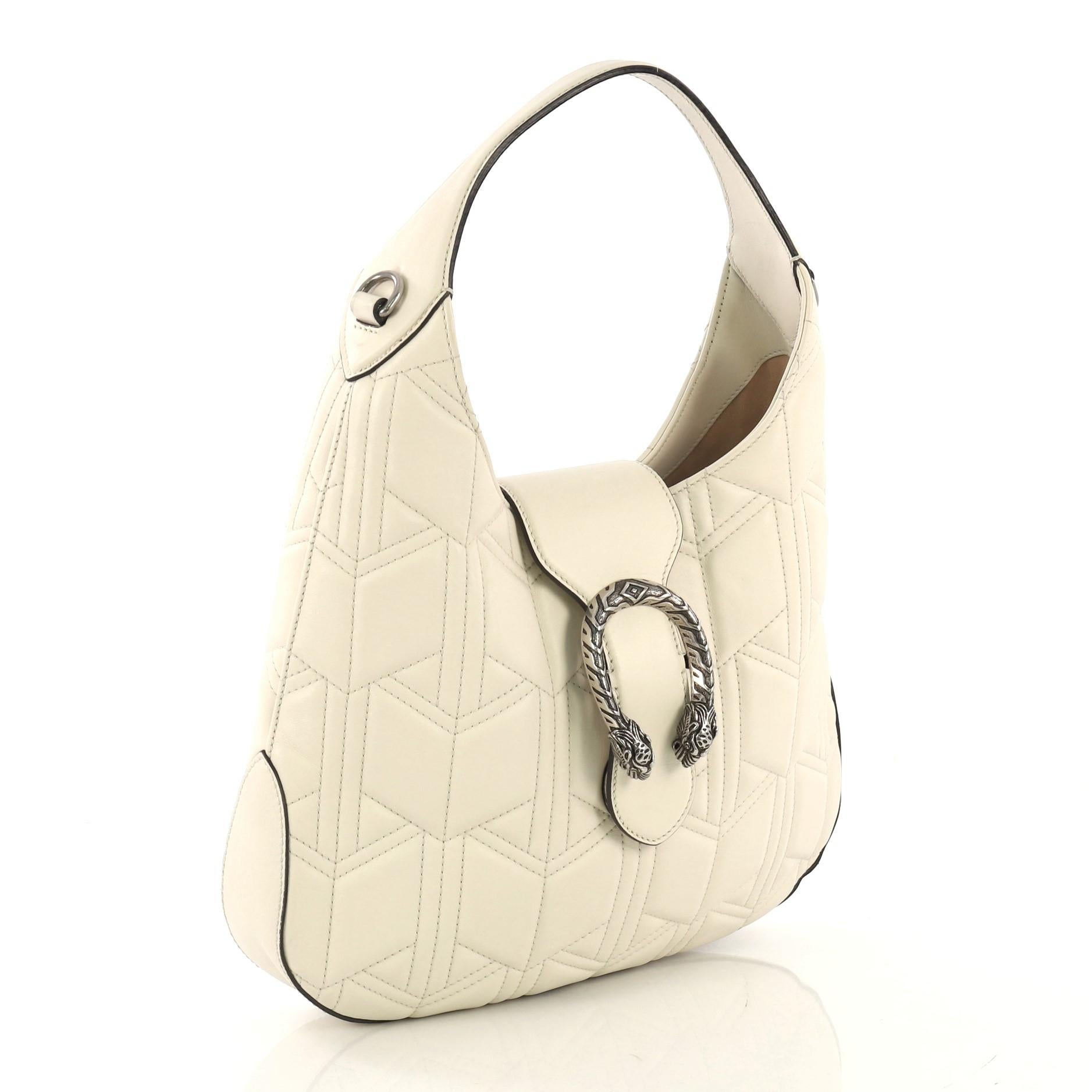 This Gucci Dionysus Hobo Matelasse Leather Small, crafted from off white matelasse leather, features a single loop leather handle, textured tiger head spur detail on its flap tab, and aged silver-tone hardware. It opens to a nude microfiber interior