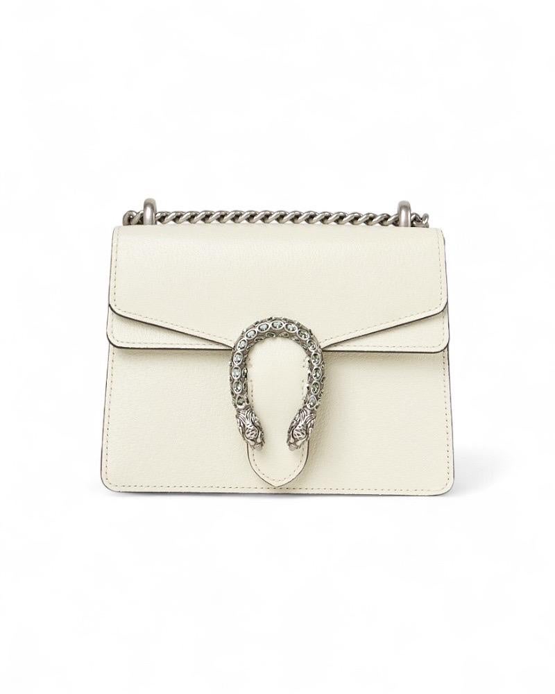 Borsa firmata Gucci, della linea Dionysus, realizzata in PELLE martellata nella sofisticata colorazione bianca, con dettagli in hardware argentato. La chiusura ad incastro con teste di tigre è un elemento distintivo di design che rende omaggio al