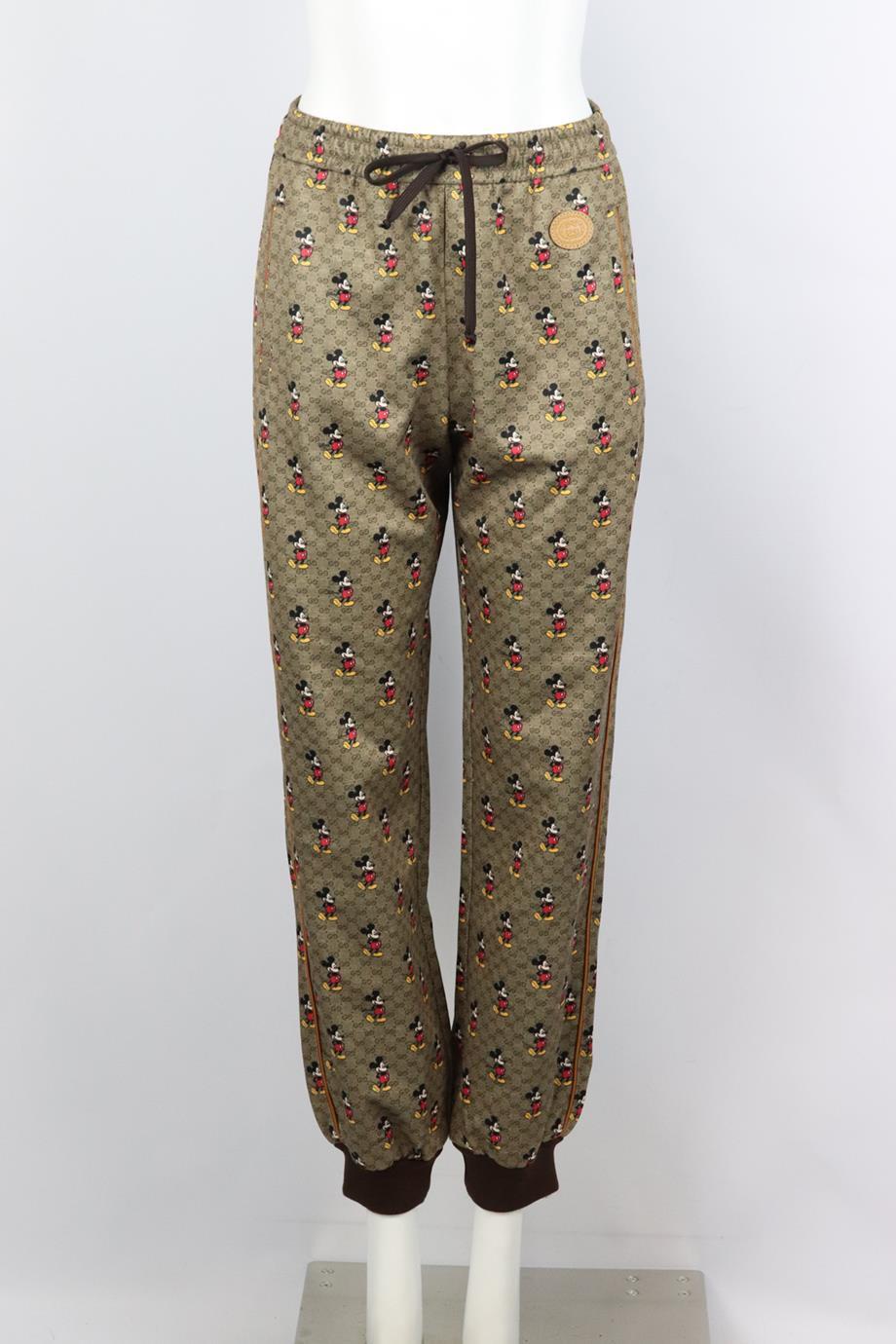 Gucci + Disney gg print tech jersey track pants. Brown. Pull on. 55% Polyester, 45% cotton; fabric2: 72% polyester, 25% polyamide, 3% elastane. Size: Small (UK 8, US 4, FR 36, IT 40). Waist: 27.5 in. Hips: 43.2 in. Length: 40.2 in. Inseam: 29.7 in.