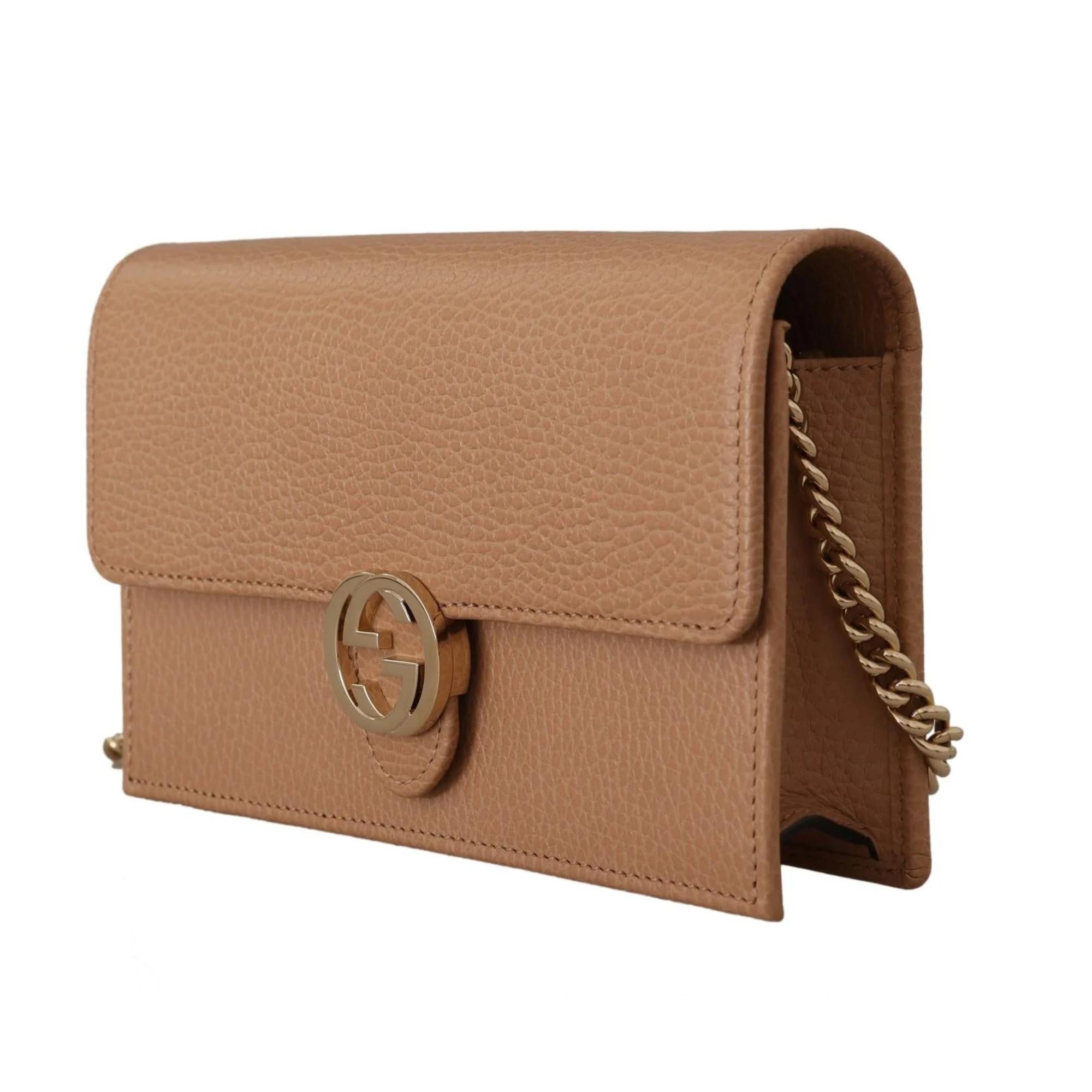 This shoulder bag is made of textured calfskin leather in a beige. This bag features a long polished gold chain shoulder strap and a Gucci GG logo on the front flap. The flap opens to a partitioned interior with matching leather and fabric in beige.