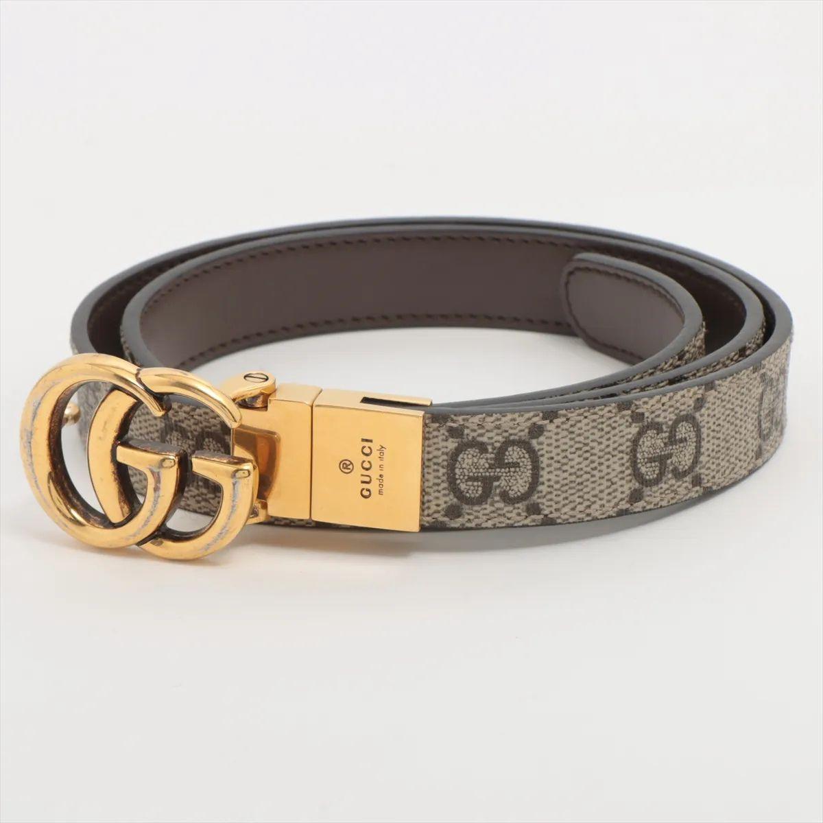 The Gucci Double G Belt in Ebony is a classic and versatile accessory crafted from smooth leather in a rich, dark brown tone. It features the iconic antiqued brass Double G logo buckle, a hallmark of the brand inspired by archival designs. The GG
