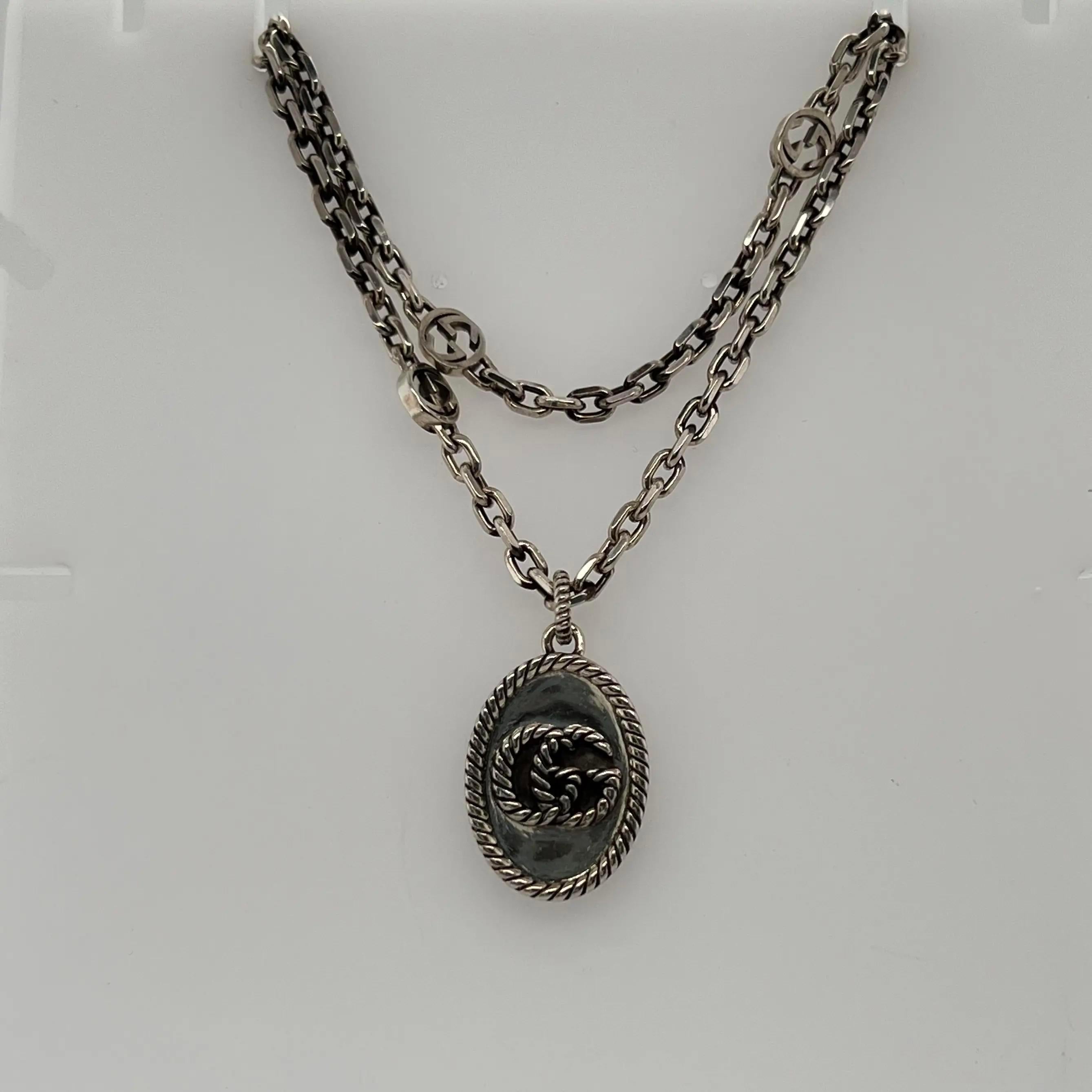 This gorgeous GUCCI pendant necklace is designed in 925 sterling silver with an aged finish. It features interlocking G motif detail on the chain with an oval-shaped Double G pendant. Secured with lobster closure. Chain length: 27 inches. Pendant