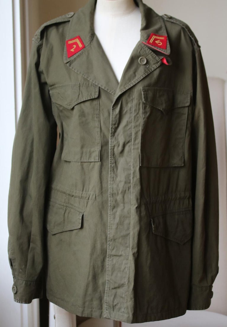 Crafted in Italy each one is made from a military green washed coated cotton and features military influenced red collar pointed appliqué with arrows and '25' print. Embroidered dragon appliqué –an image that the Chinese believe to be a symbol of