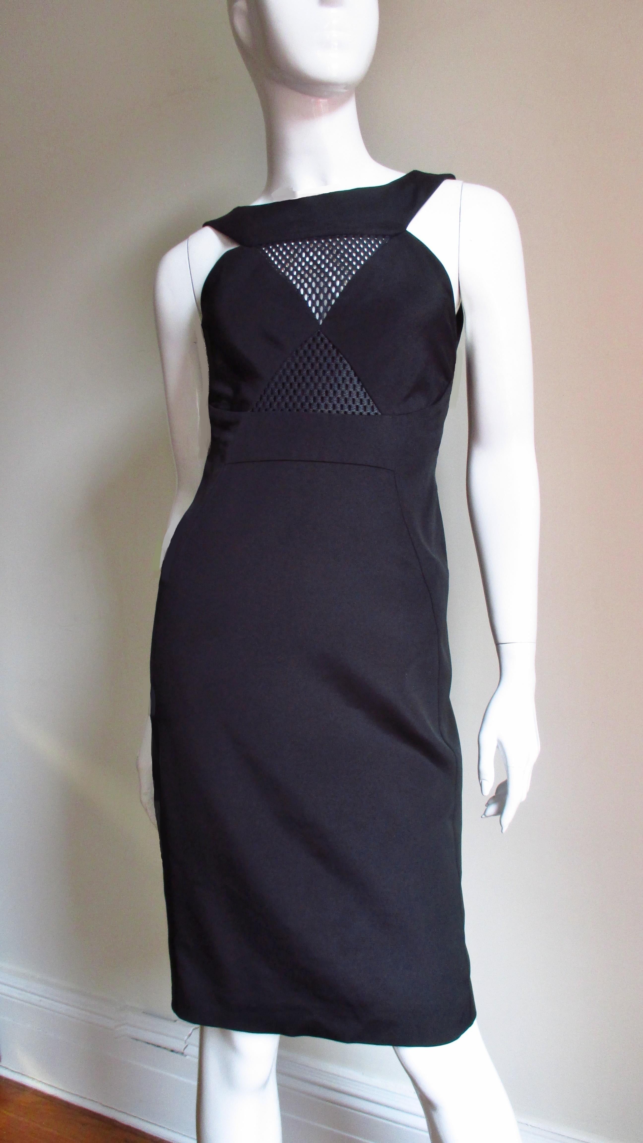 A fabulous stretch bandage fabric bodycon black dress from Gucci.  It has cut in shoulders, a crew neckline with a triangular net covered cut out at the upper chest and elongated diamond shaped mesh covered cut outs at the side waist and framing the